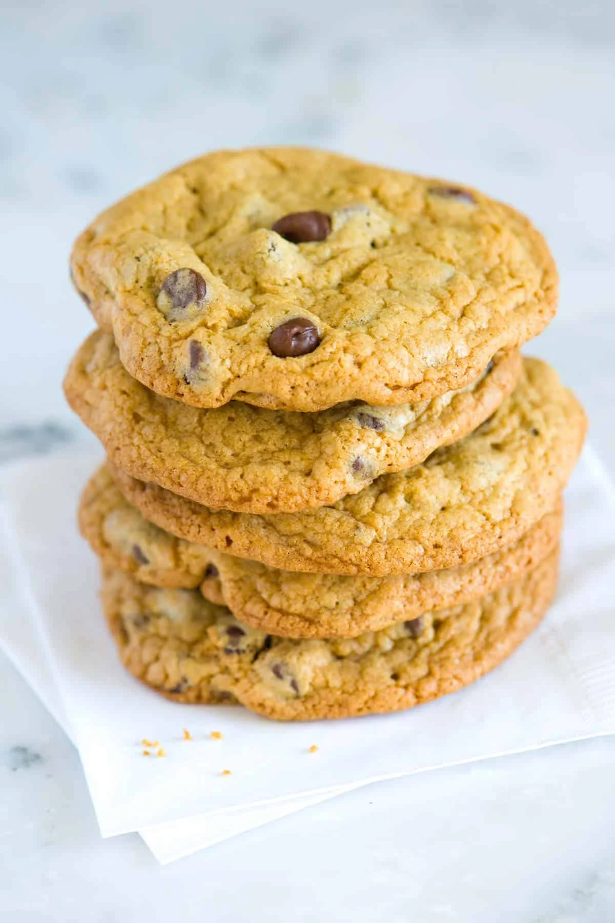 Freshly baked chocolate chip cookies stacked on a napkin