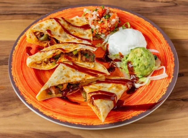 Delicious Mexican quesadillas served with guacamole and salsa on a vibrant plate