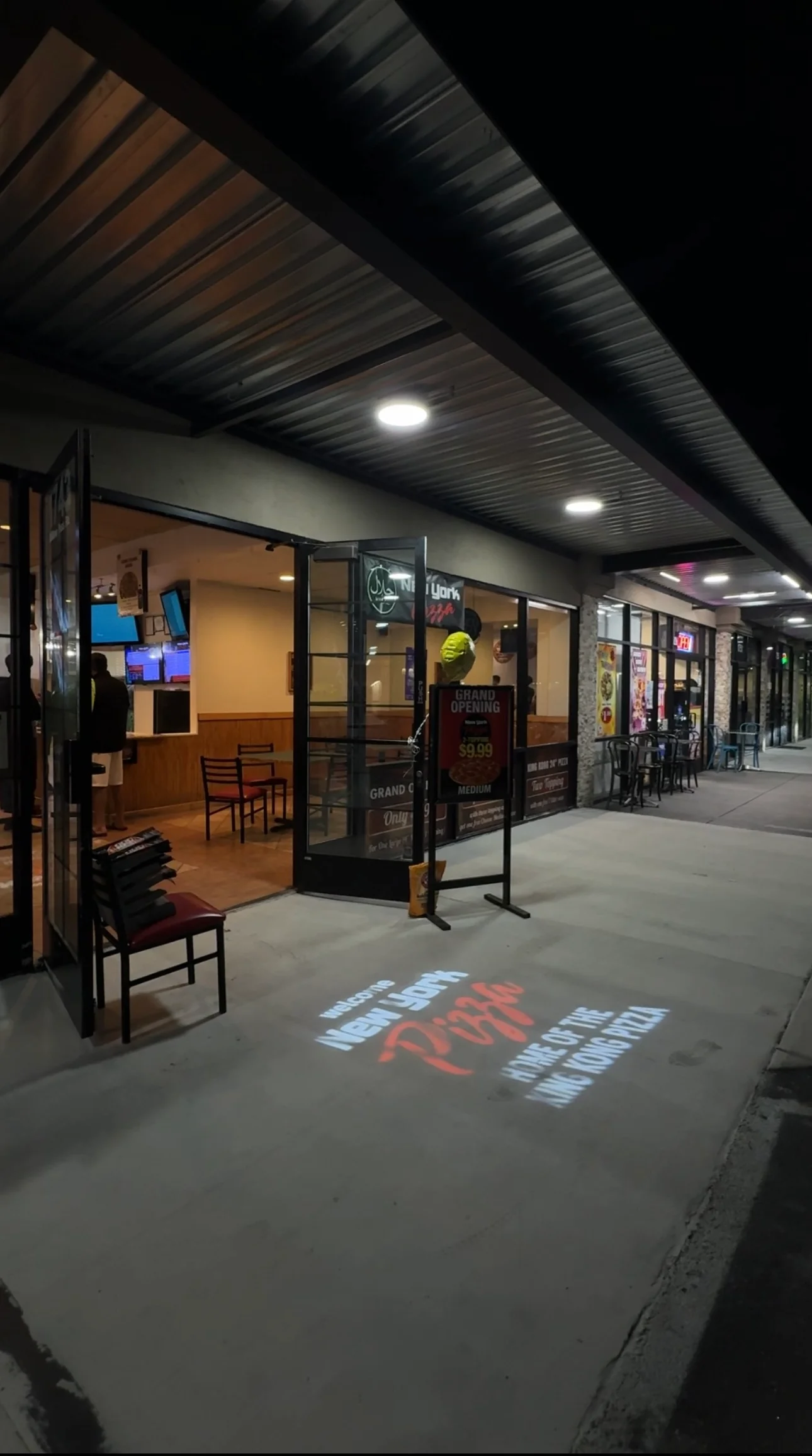 Exterior view of New York Pizza restaurant with grand opening sign