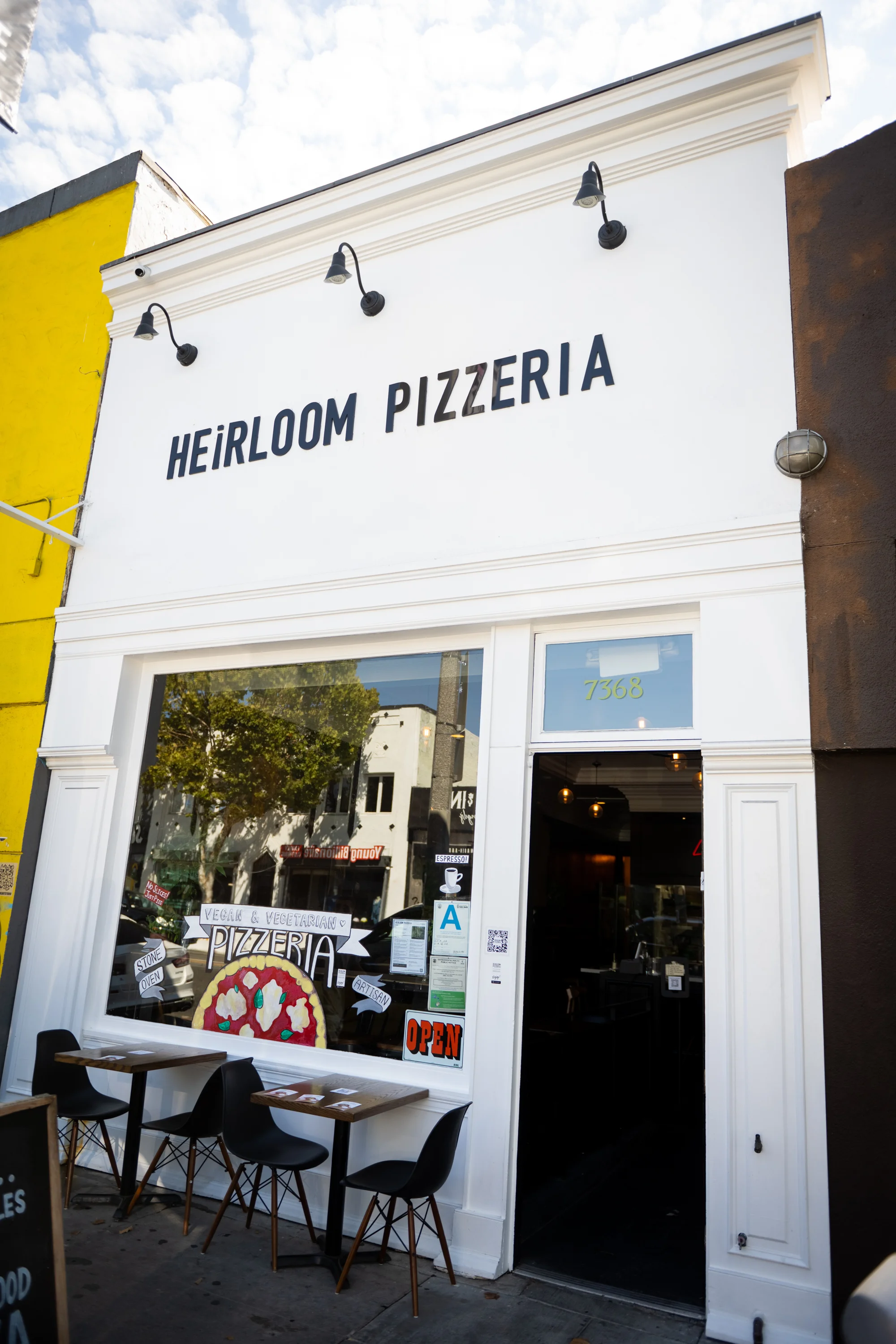Exterior of Heirloom Pizzeria with open sign and outdoor seating
