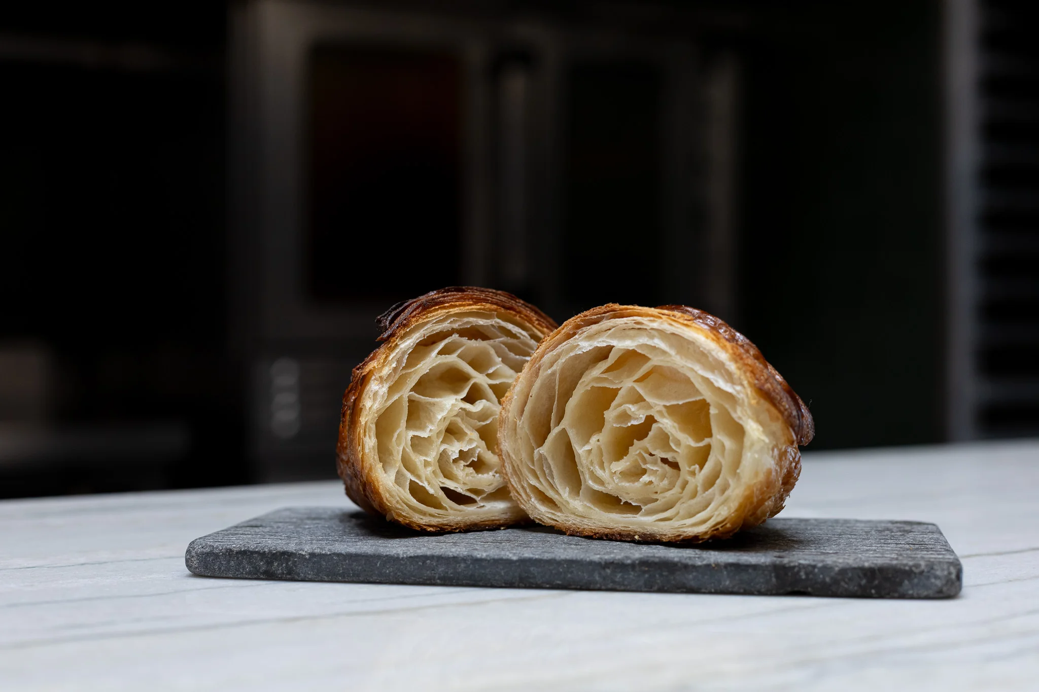 Flaky French croissant cut in half on a slate board