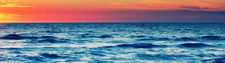Vibrant sunset over the ocean with waves lapping the shore