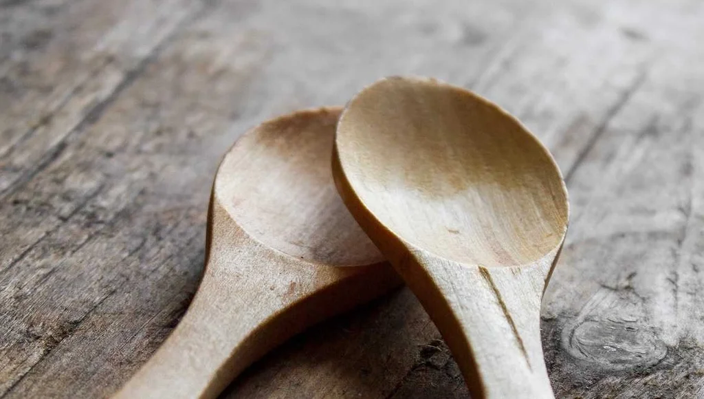 Two wooden spoons resting on a rustic wooden table