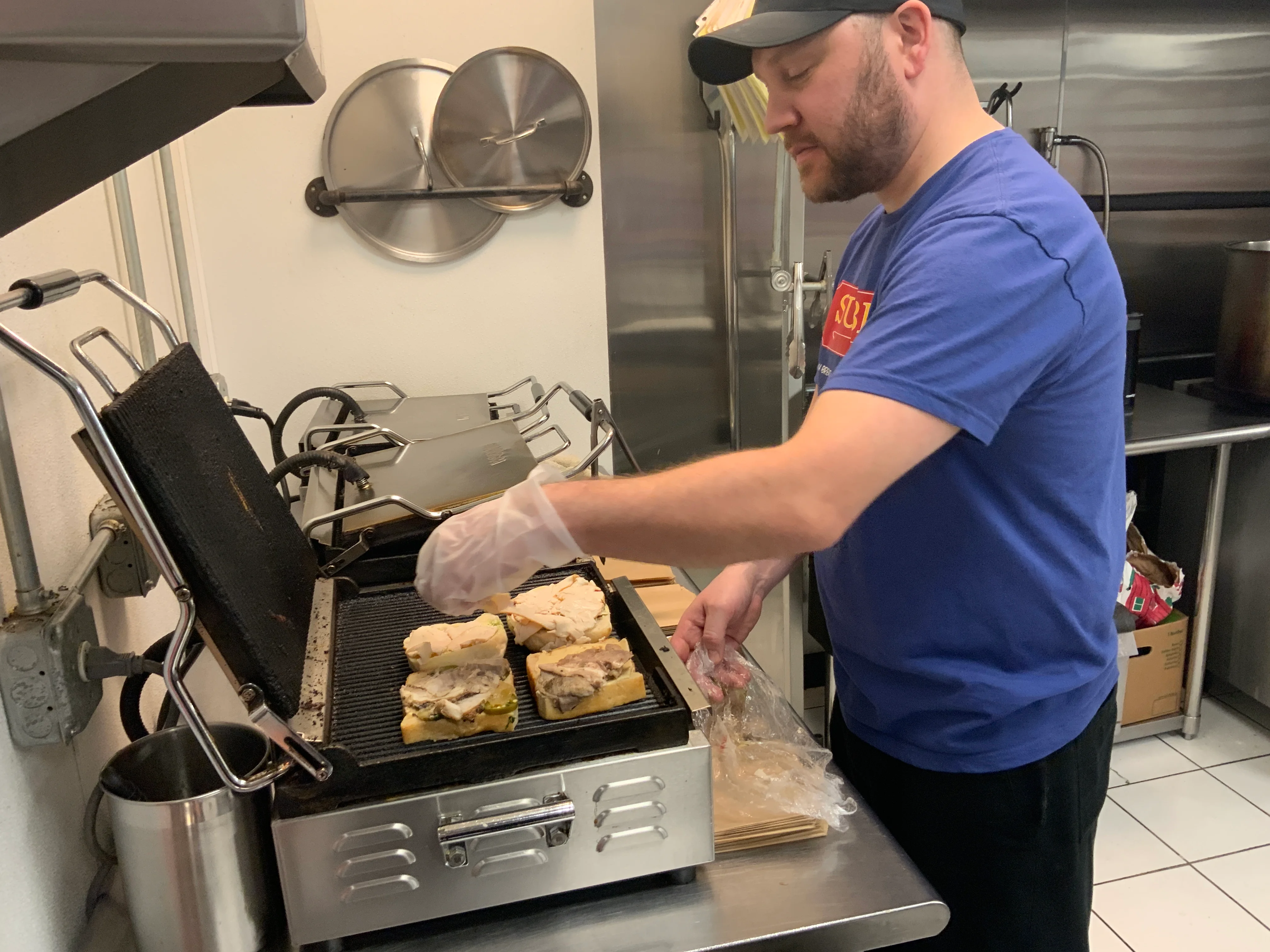 Chef Mike puts the panini on the grill to heat them up.