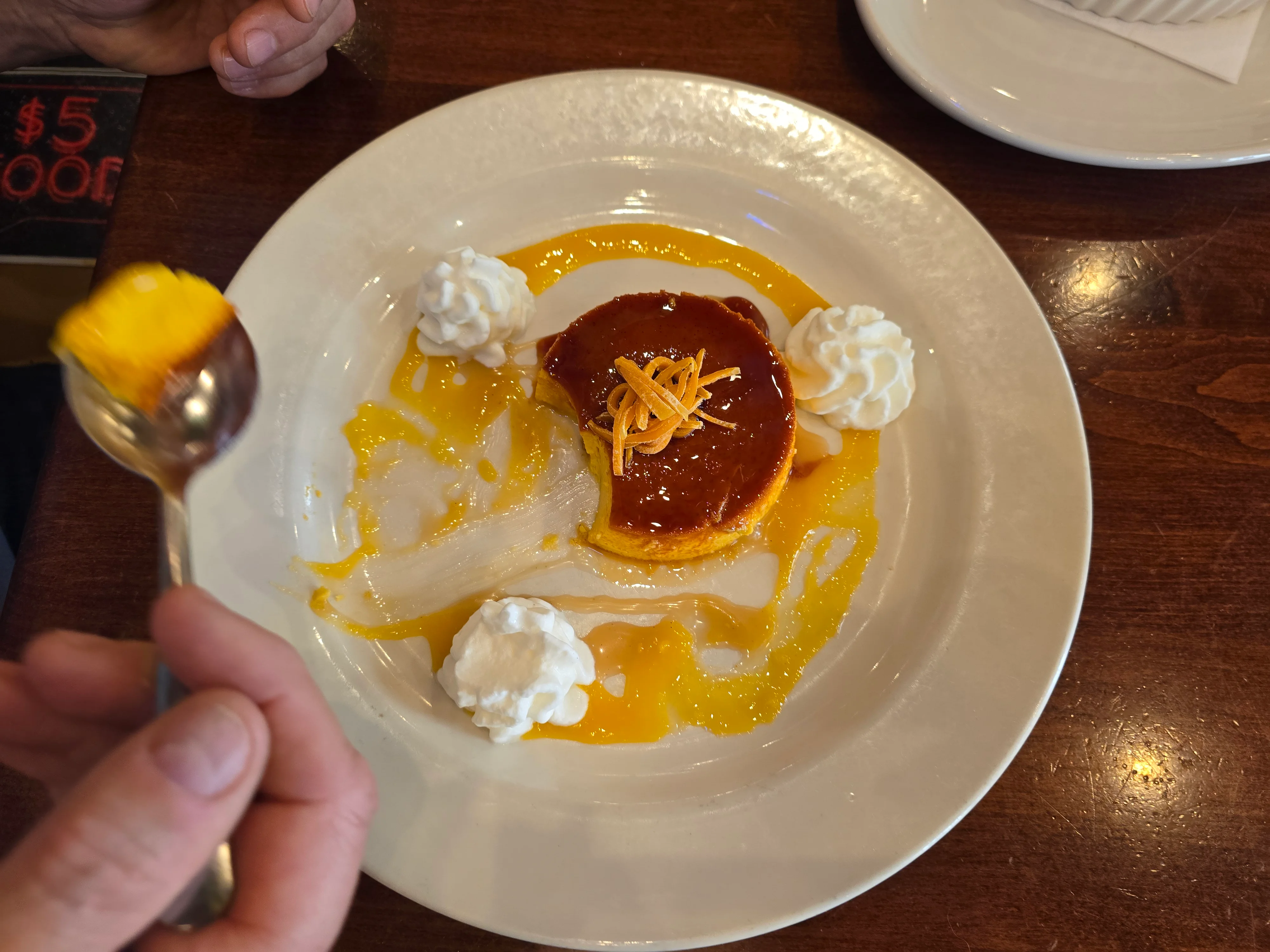 Dessert plate with flan, whipped cream, and mango sauce.