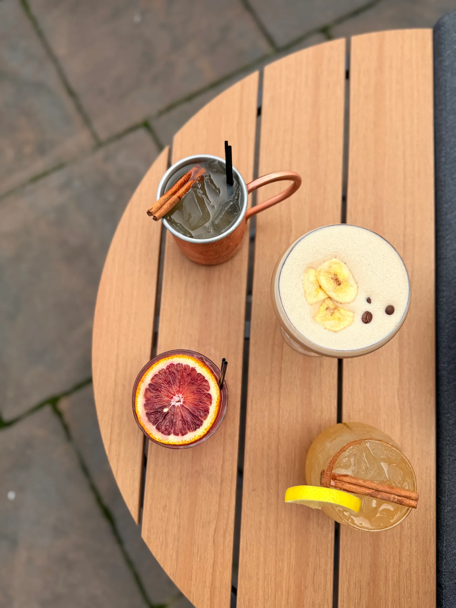 Overhead selection of craft cocktails with citrus, cinnamon, and banana garnishes