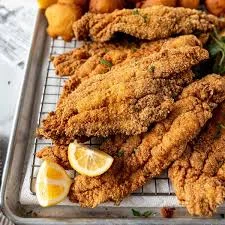 A tray filled with fried fish fillets, garnished with fresh lemon slices.