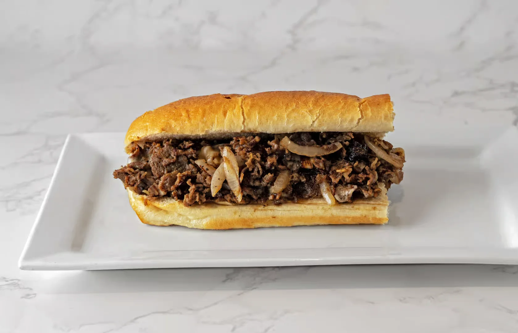 Mouthwatering cheesesteak at Smackin Js Deli and Grill in Pompano Beach with tender sliced beef, sautéed onions, and melted cheese in a fresh hoagie roll.