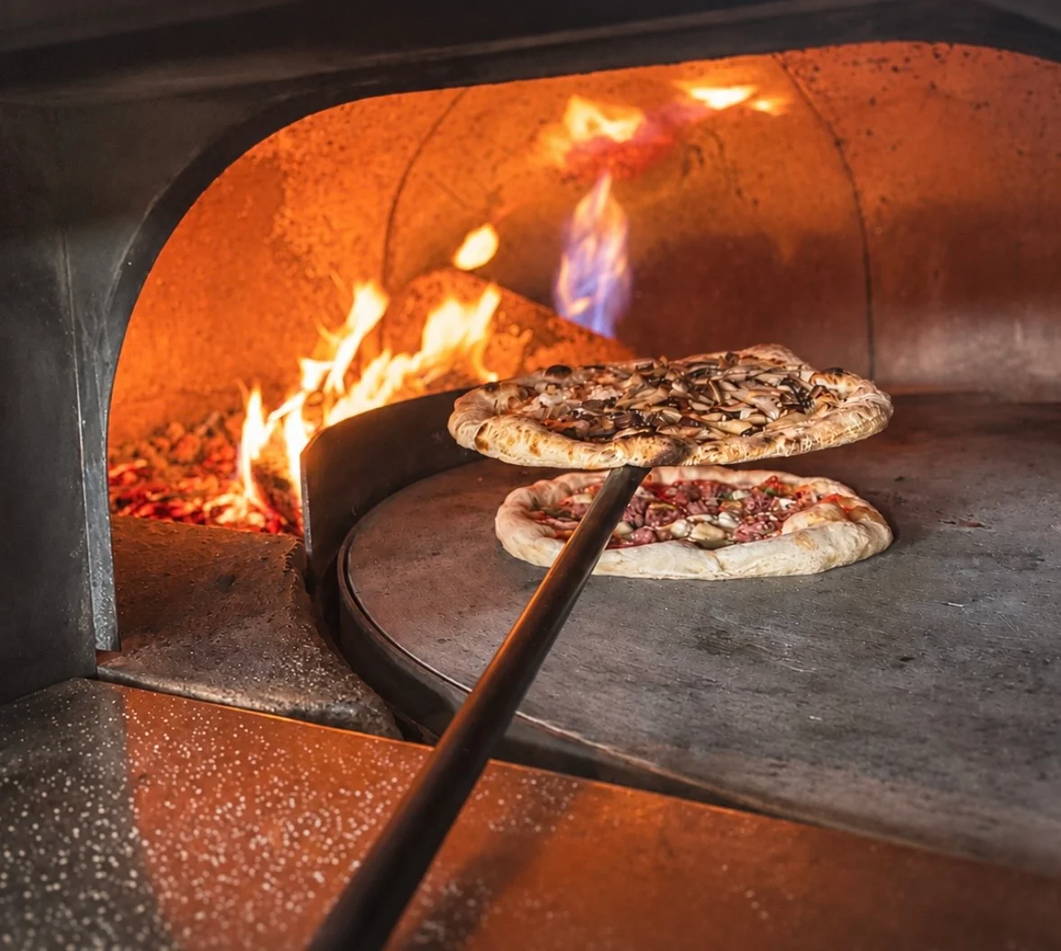 Wood-fired Margherita pizza baking in a traditional oven