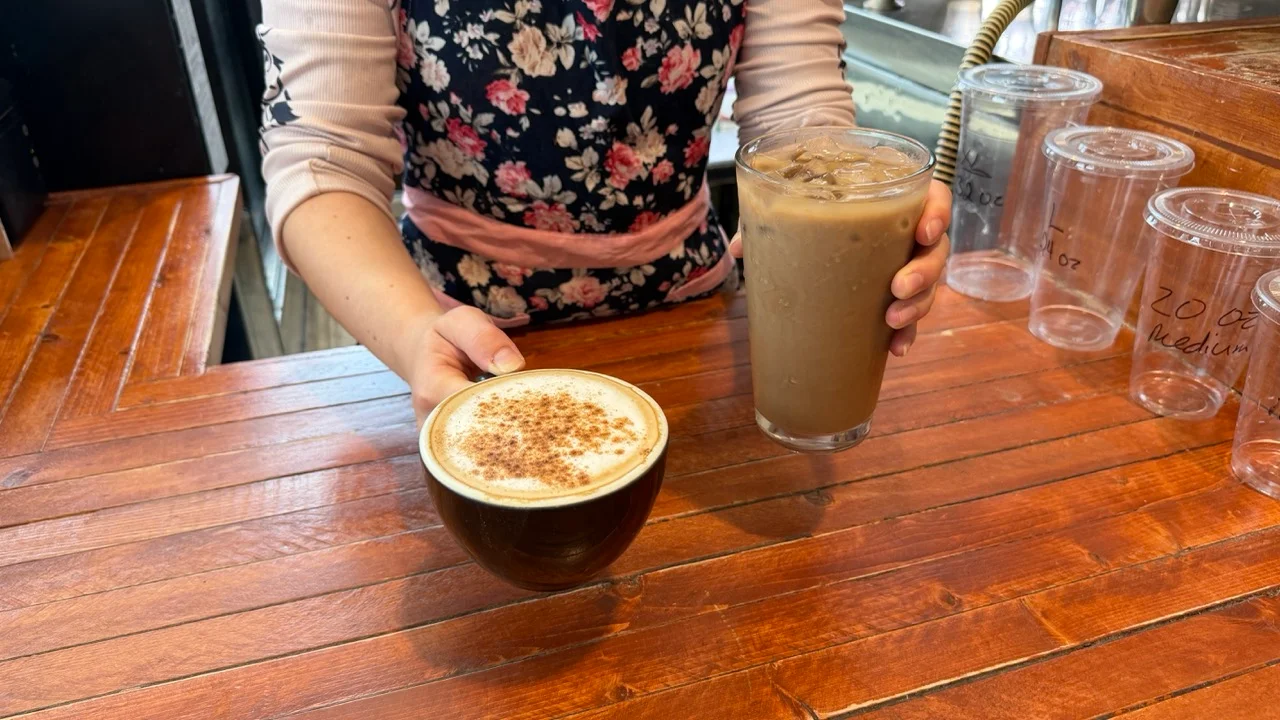 Barista serving cappuccino and iced coffee at a cozy café