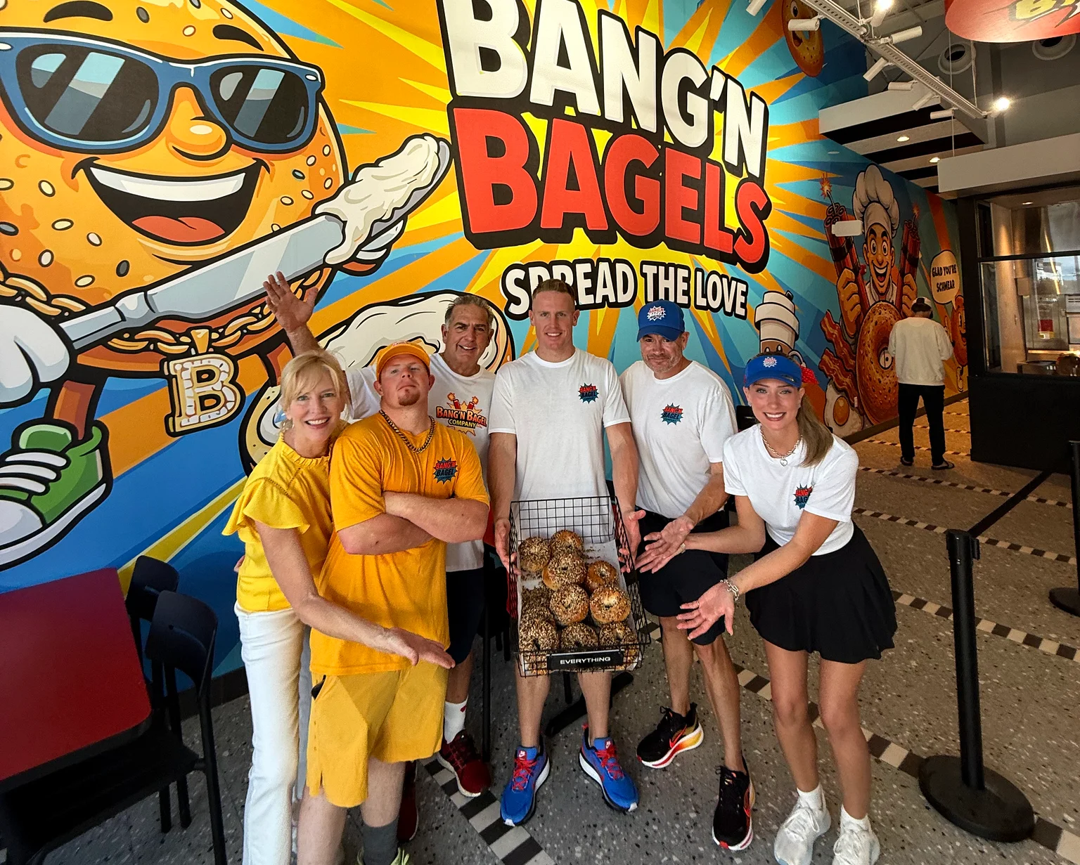 Group of people celebrating at Bang'n Bagels with a basket of bagels.
