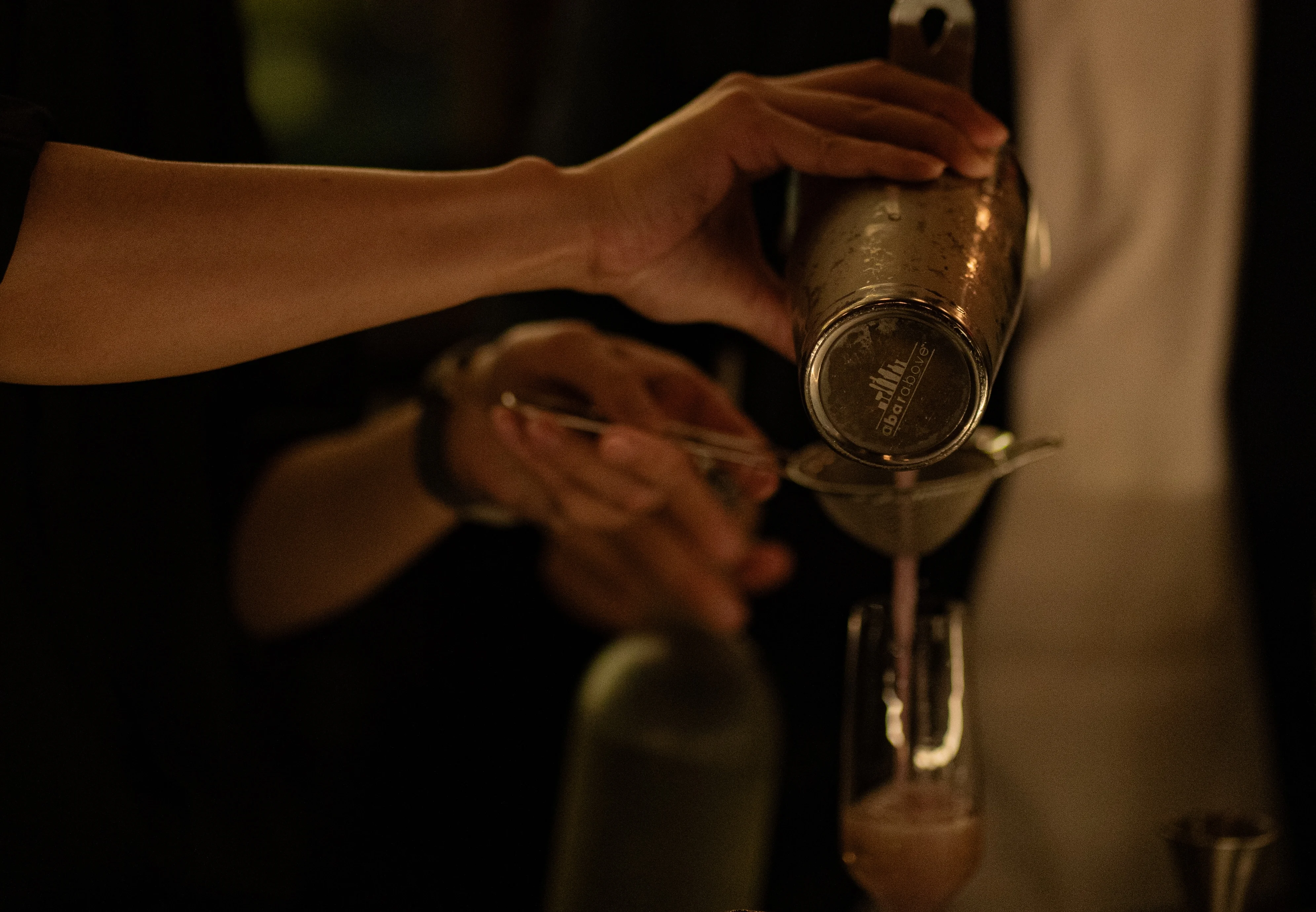 Bartender pouring a cocktail through a strainer