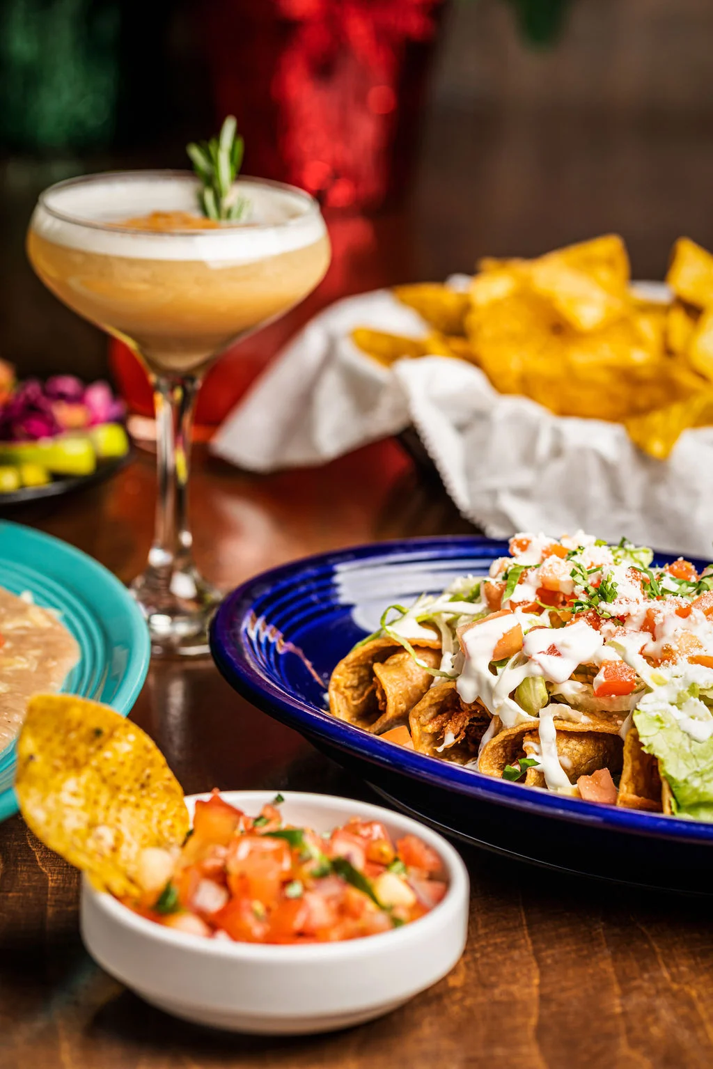 Plate of Mexican tacos with toppings and a cocktail in a vibrant setting