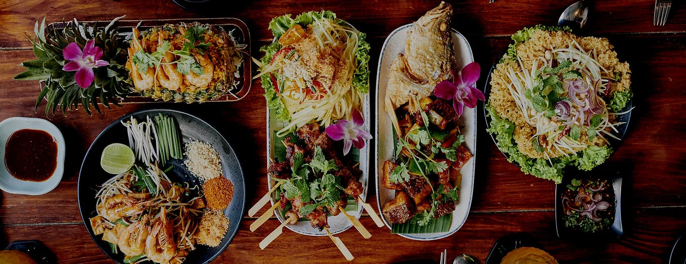 Thai feast featuring pad thai, grilled meats, and fresh herbs