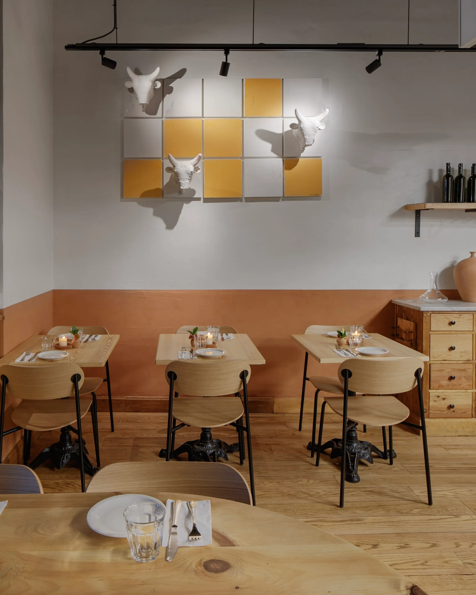 Tables for two by the tiled wall at Chama Mama Brooklyn Heights