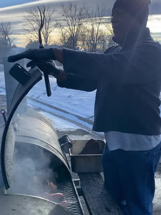 Pitmaster tending to barbecue smoker in winter