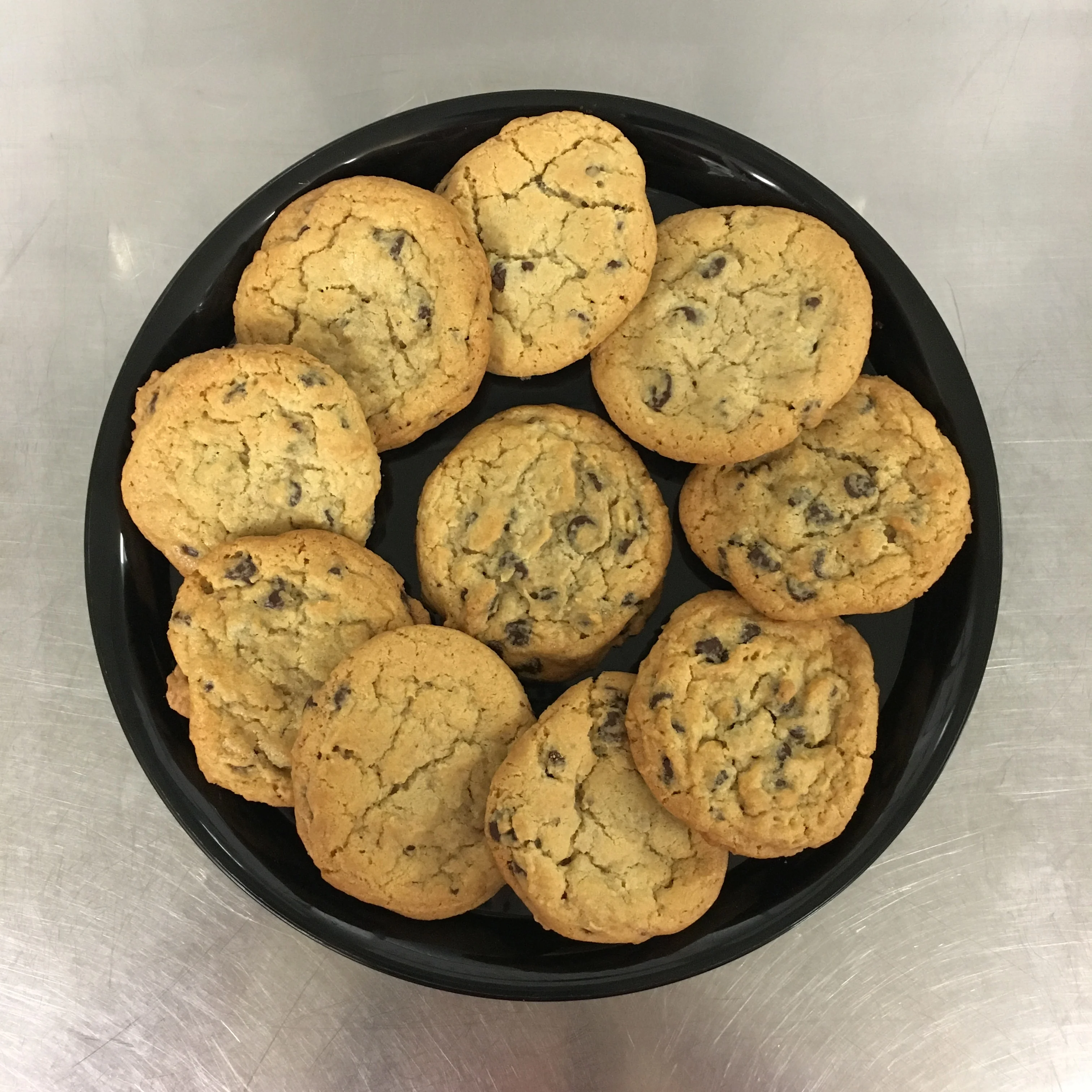 Freshly baked chocolate chip cookies on a black plate