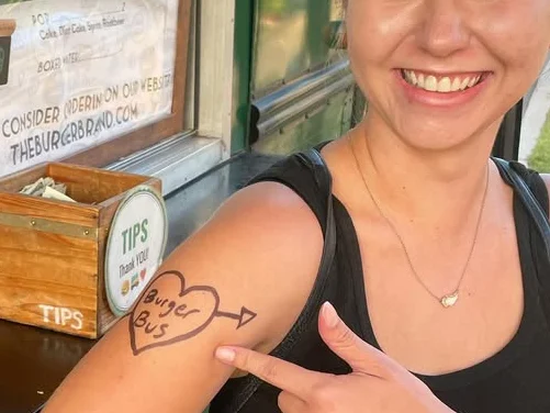 Smiling woman showing tattoo at food truck with menu