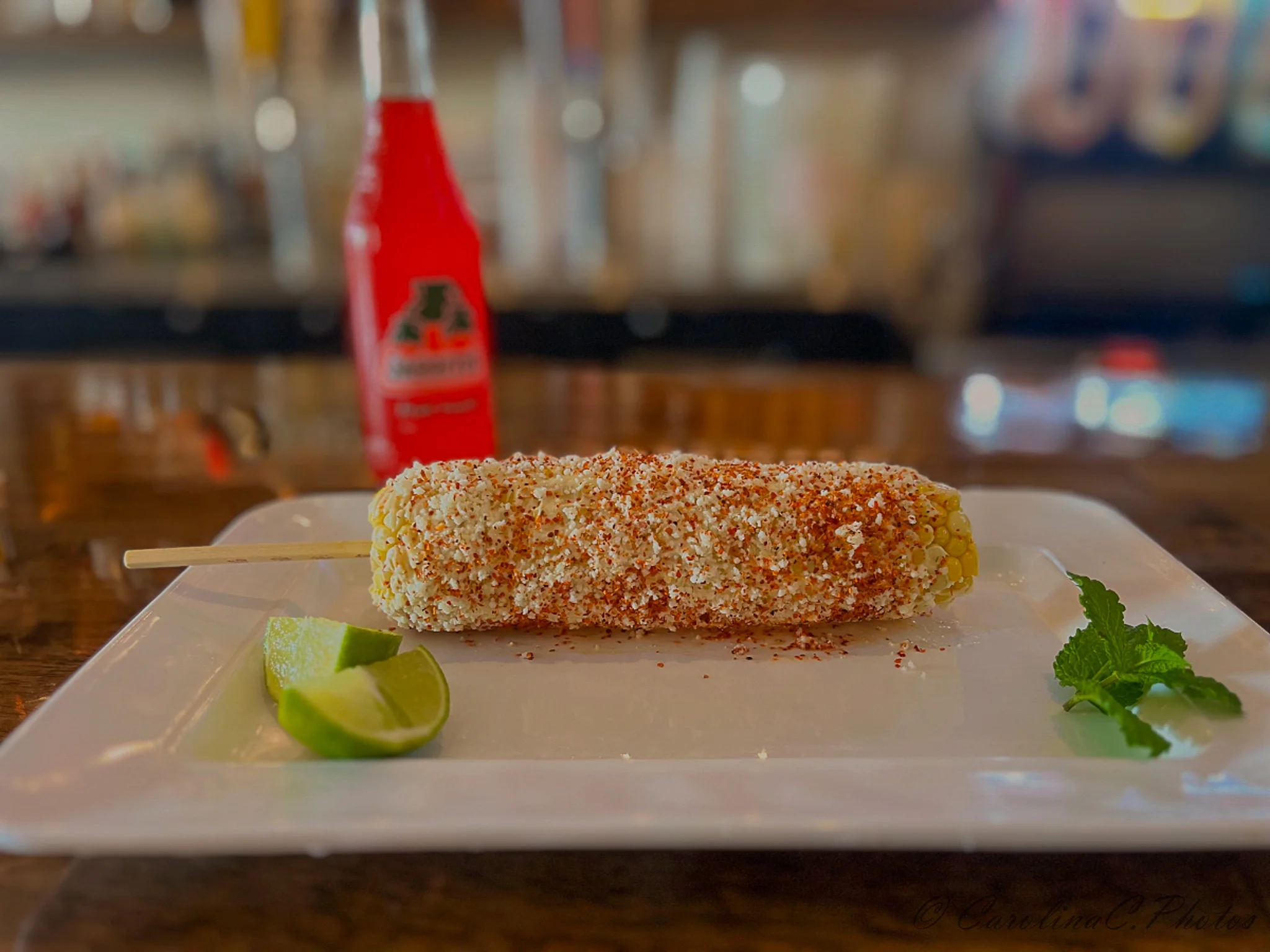 Mexican elote topped with cheese and spices on a plate