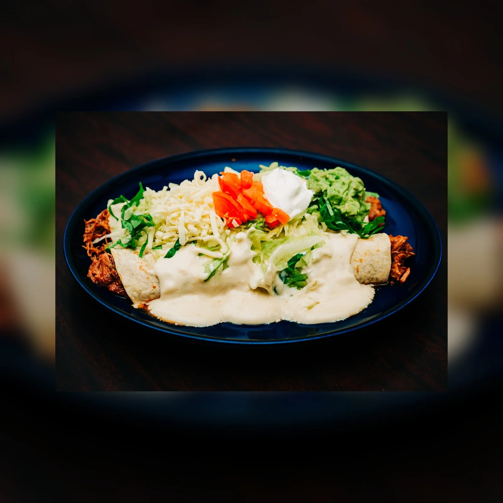 Plate of enchiladas smothered in creamy sauce and fresh toppings