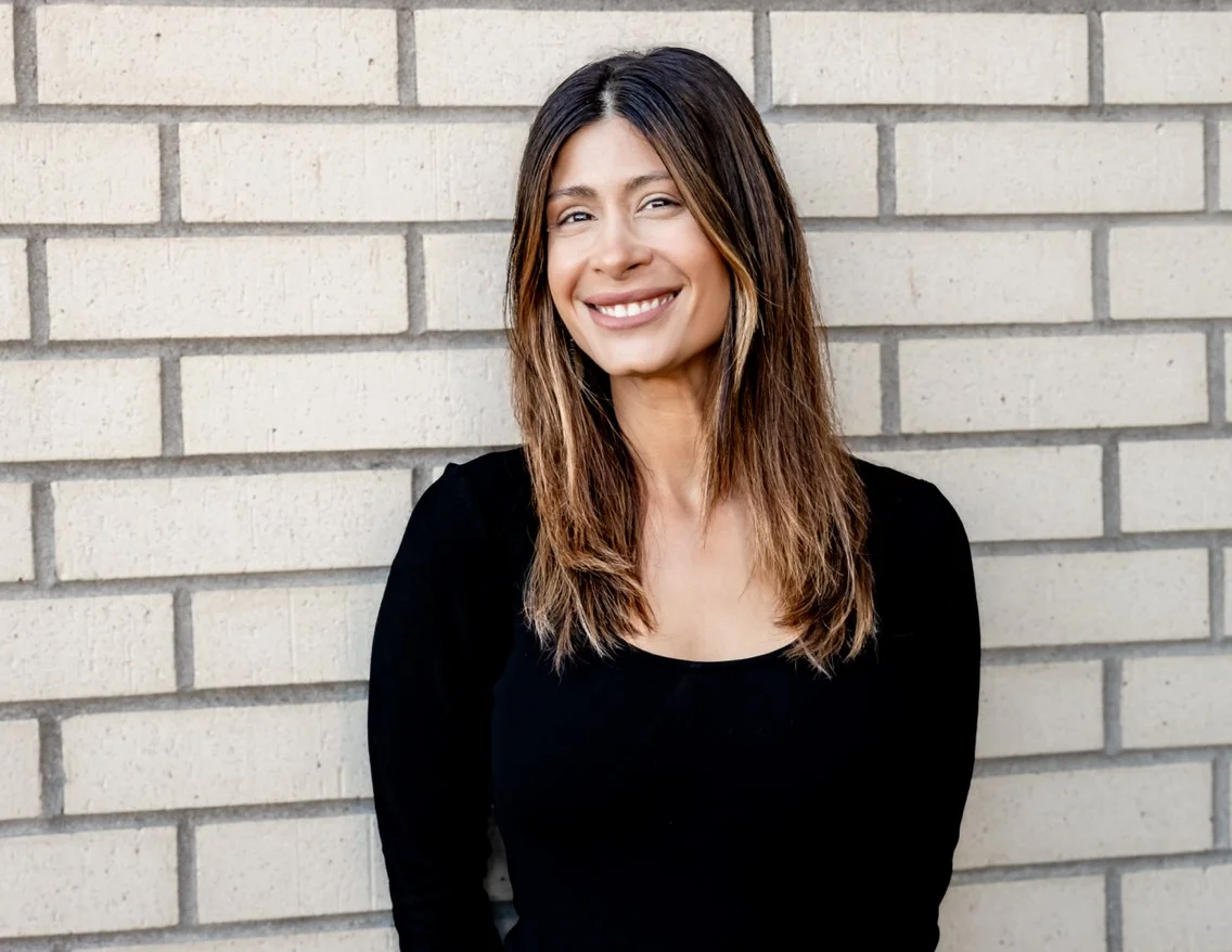 Smiling woman in a black top against a brick wall