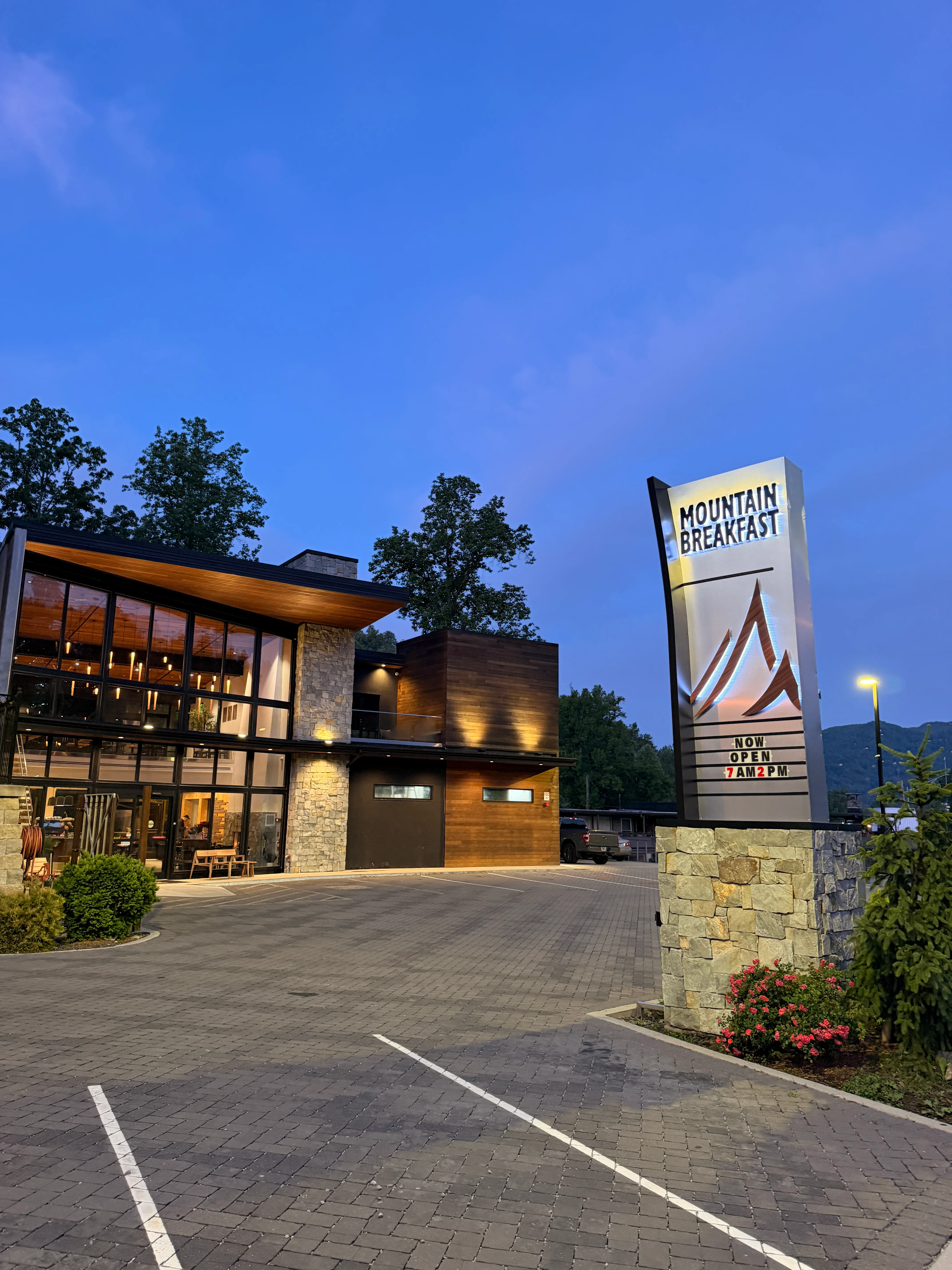 Modern restaurant exterior at dusk with mountain views
