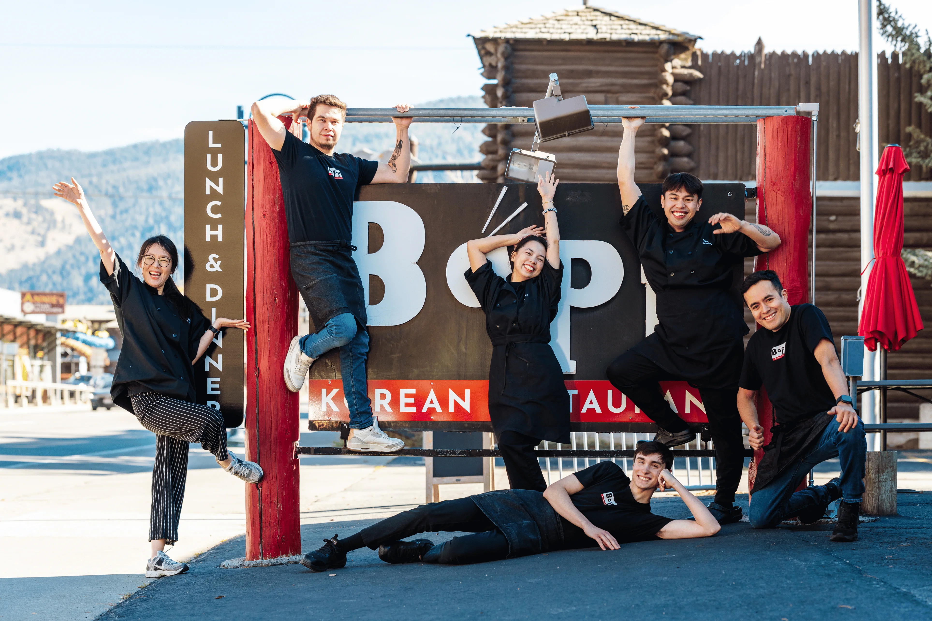 Cheerful restaurant staff in front of Bop Korean restaurant sign
