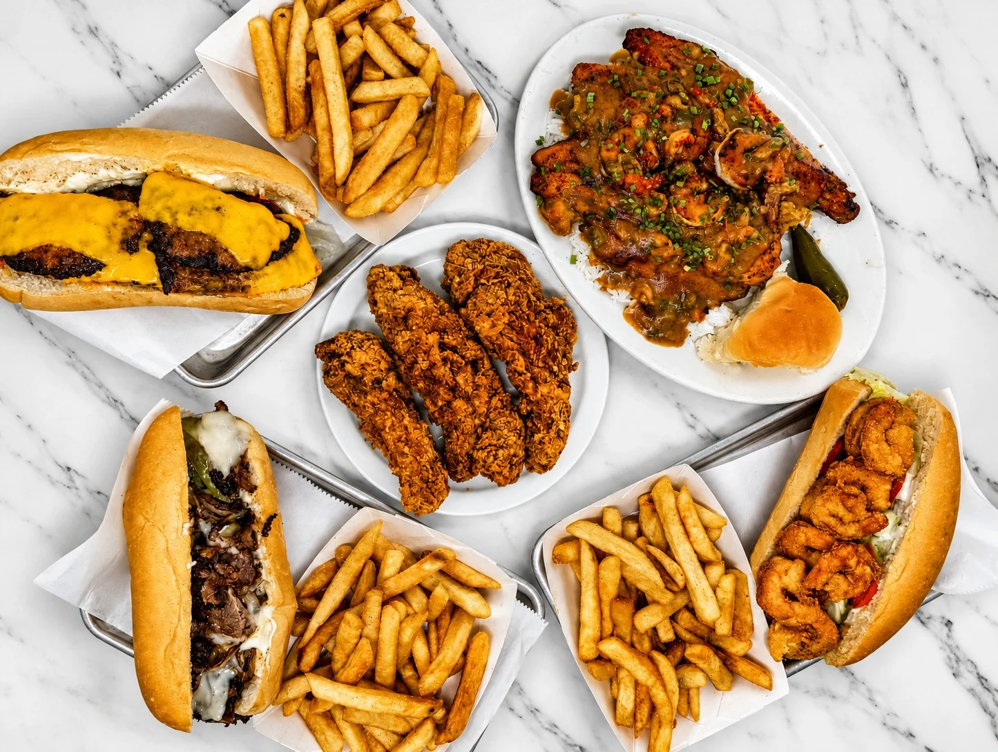 Assorted sandwiches and fried chicken platter on a marble table