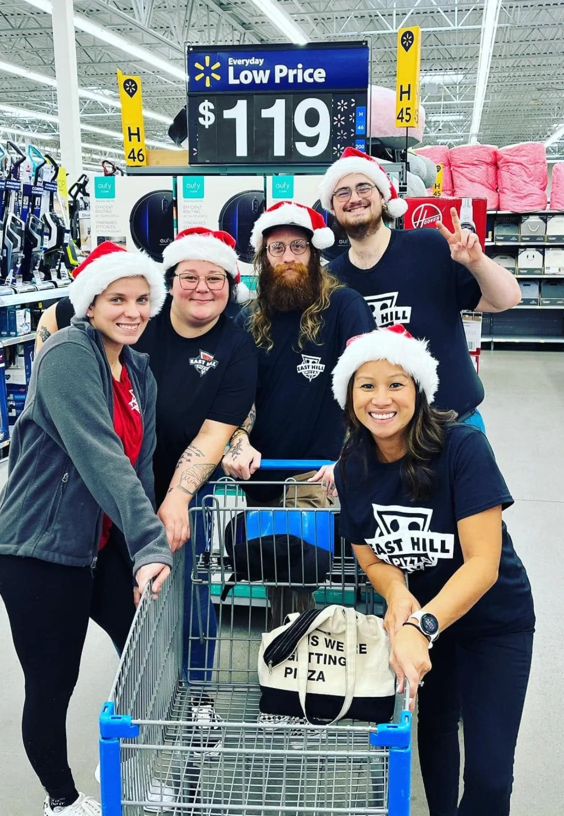 Restaurant team wearing Santa hats with a shopping cart in a retail store