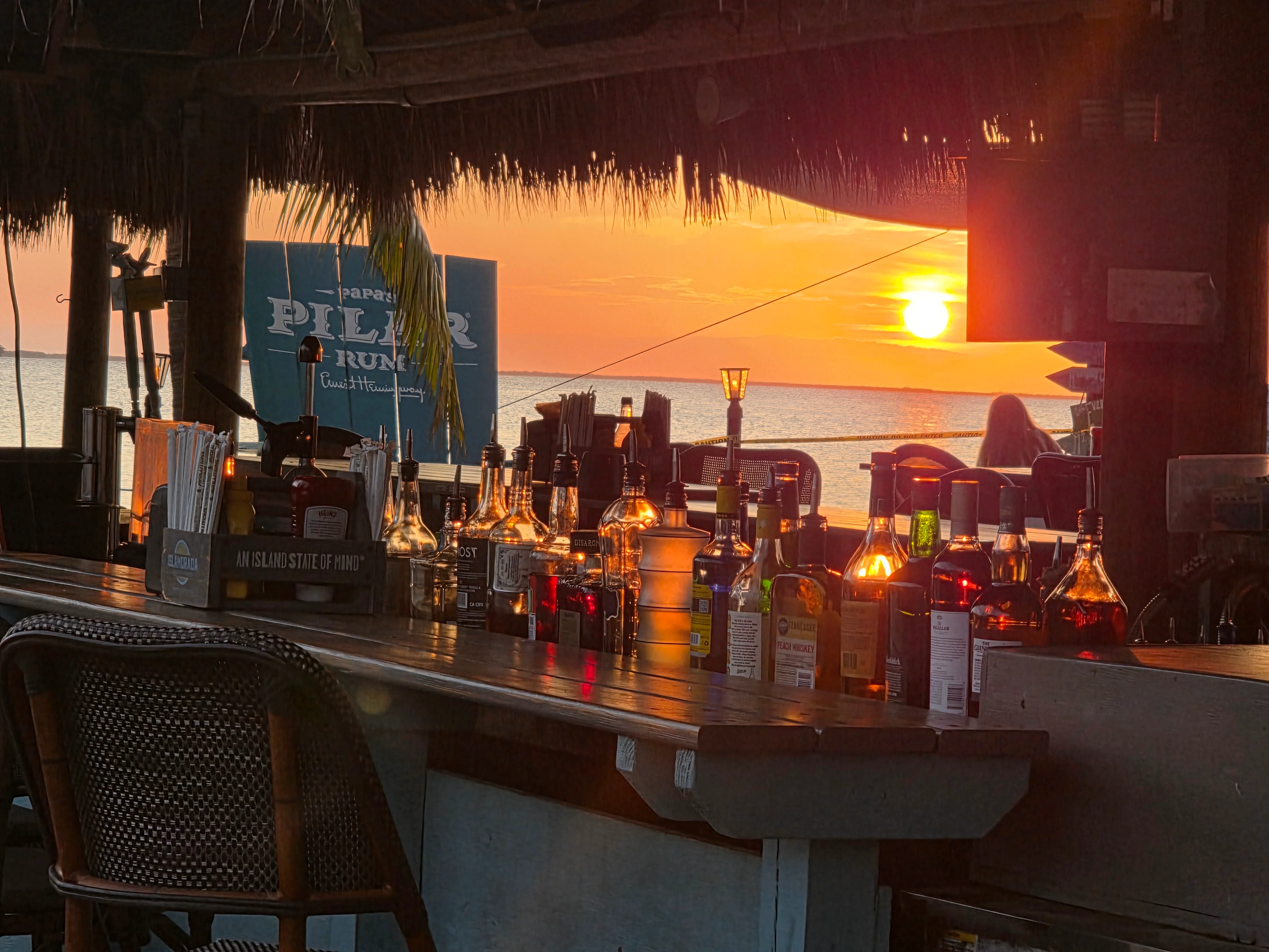 Sunset view from a beach bar with cocktails and rum bottles