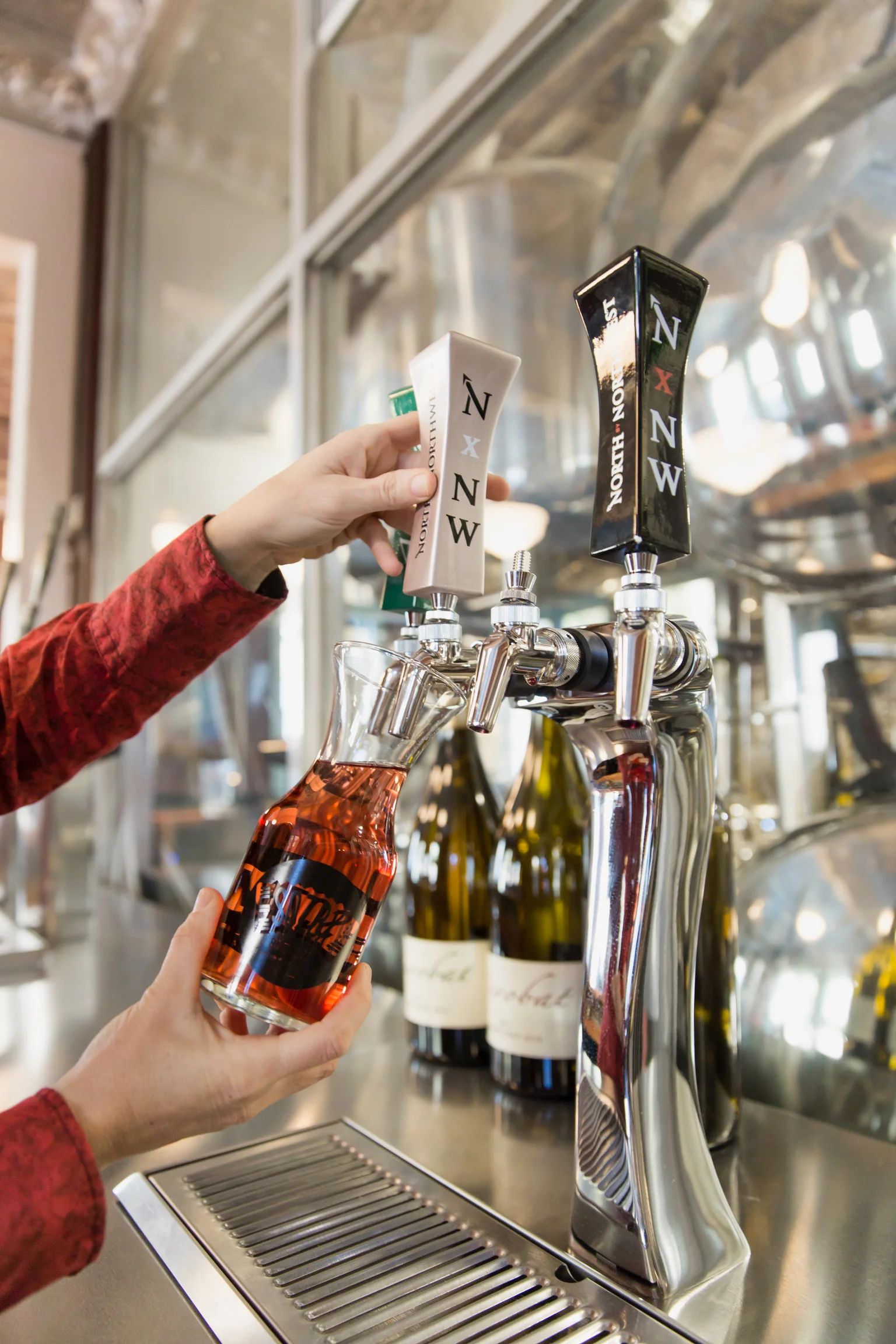 Bartender pouring wine from a tap into a glass carafe