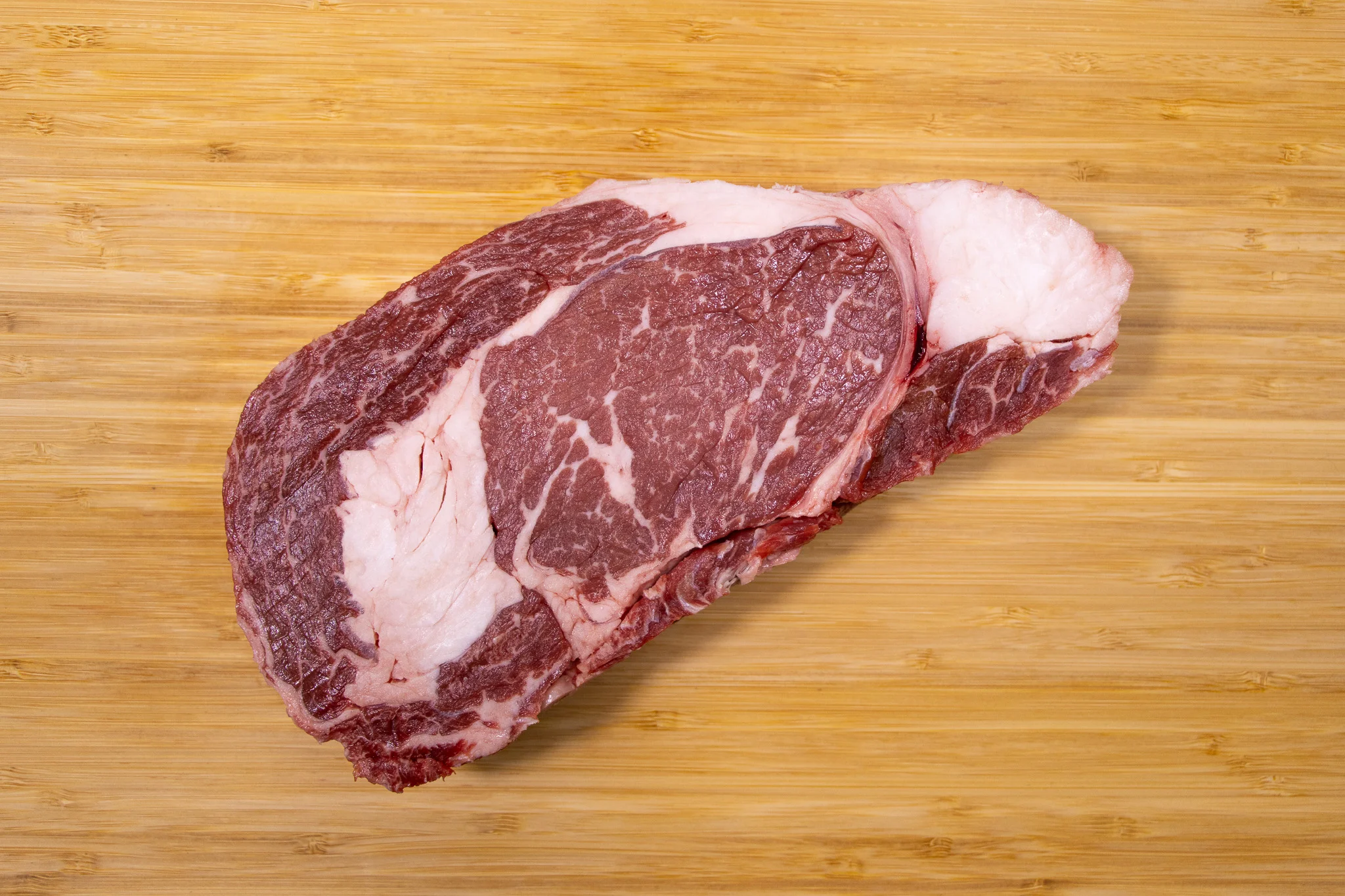 Raw ribeye steak on a wooden cutting board