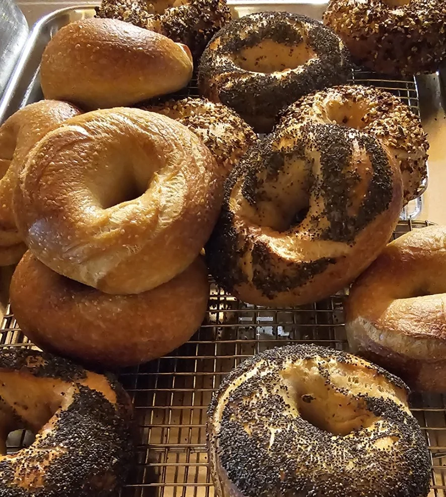 A delicious bagel with cream cheese and toppings on a wooden table.