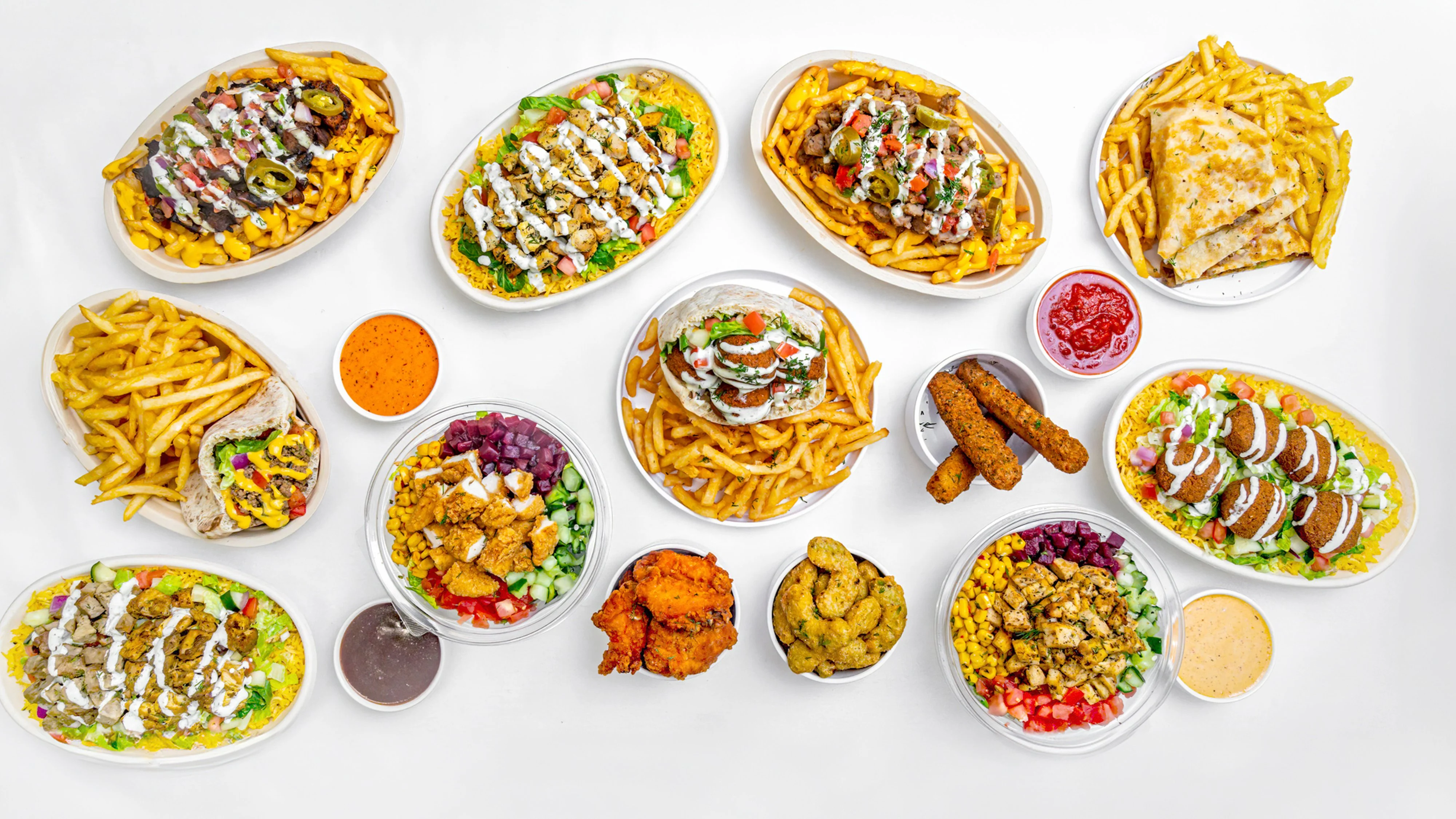 Overhead spread of Middle Eastern shawarma, falafel, rice bowls, and loaded fries