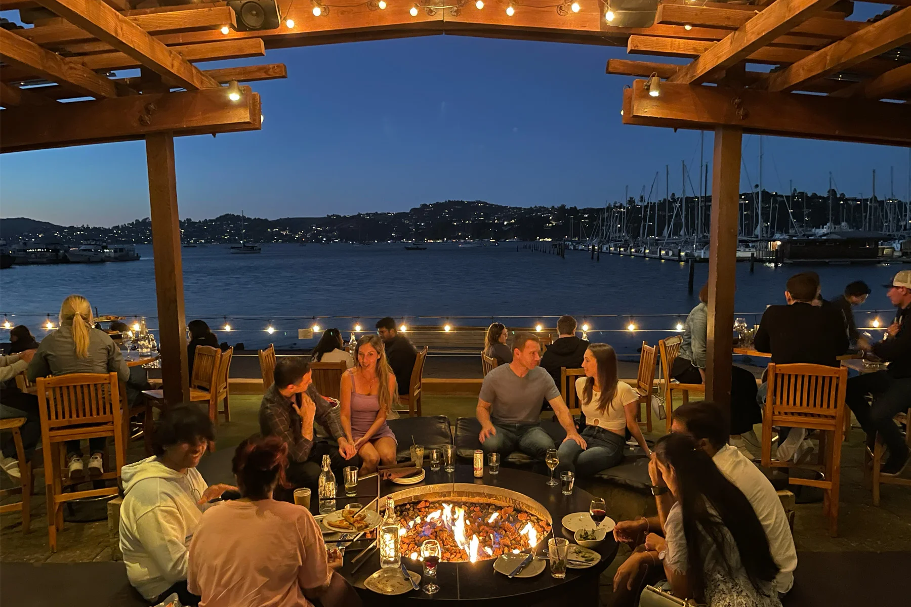friends enjoy dining around Bar Bocce's fire pit at night