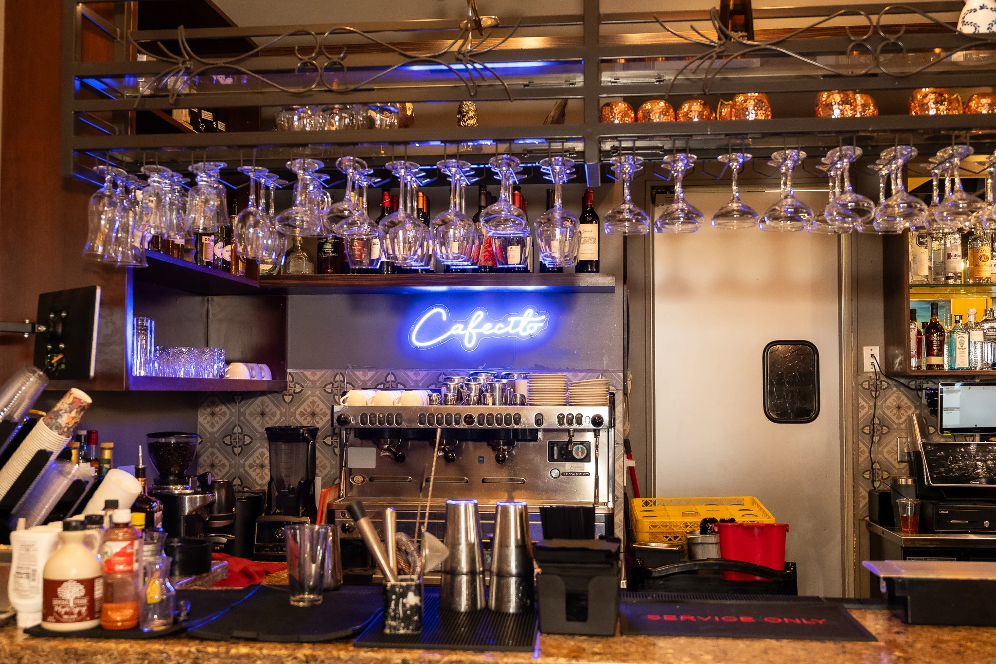 Modern bar counter with neon coffee sign and glassware