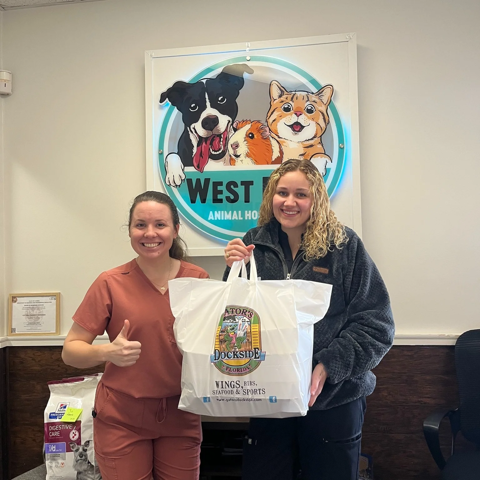 Two people standing holding up a Gator's takeout bag