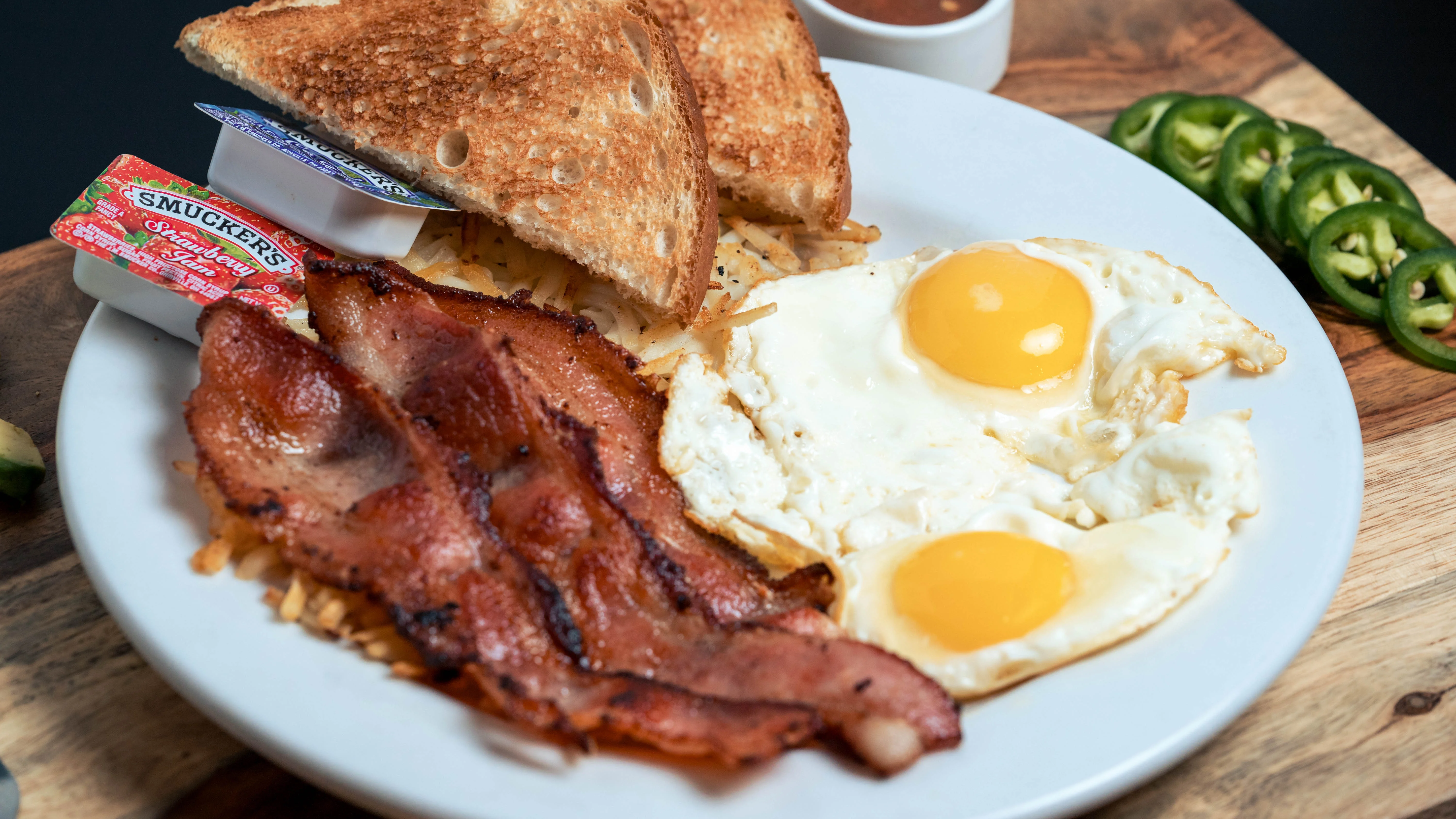 Classic American breakfast plate with eggs, bacon, toast, and hash browns