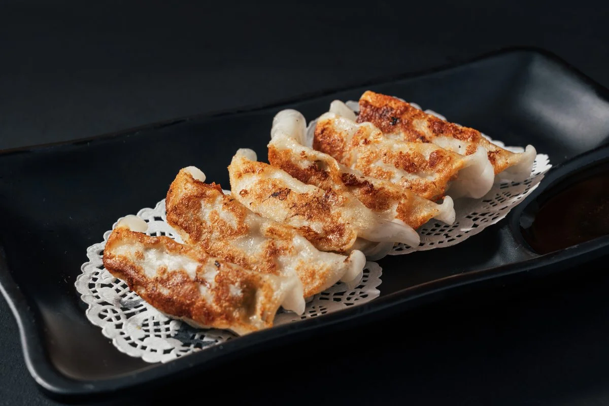 Delicious gyoza dumplings served on a plate with dipping sauce.