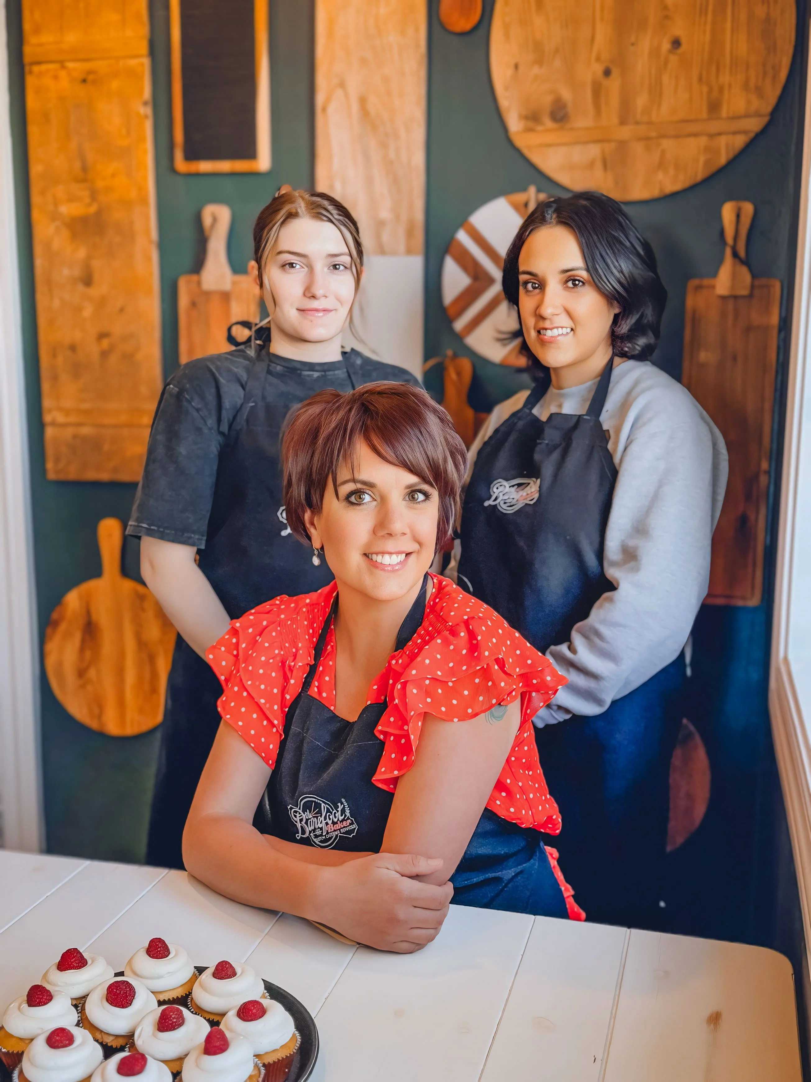 Bakers posing with cupcakes in a cozy bakery