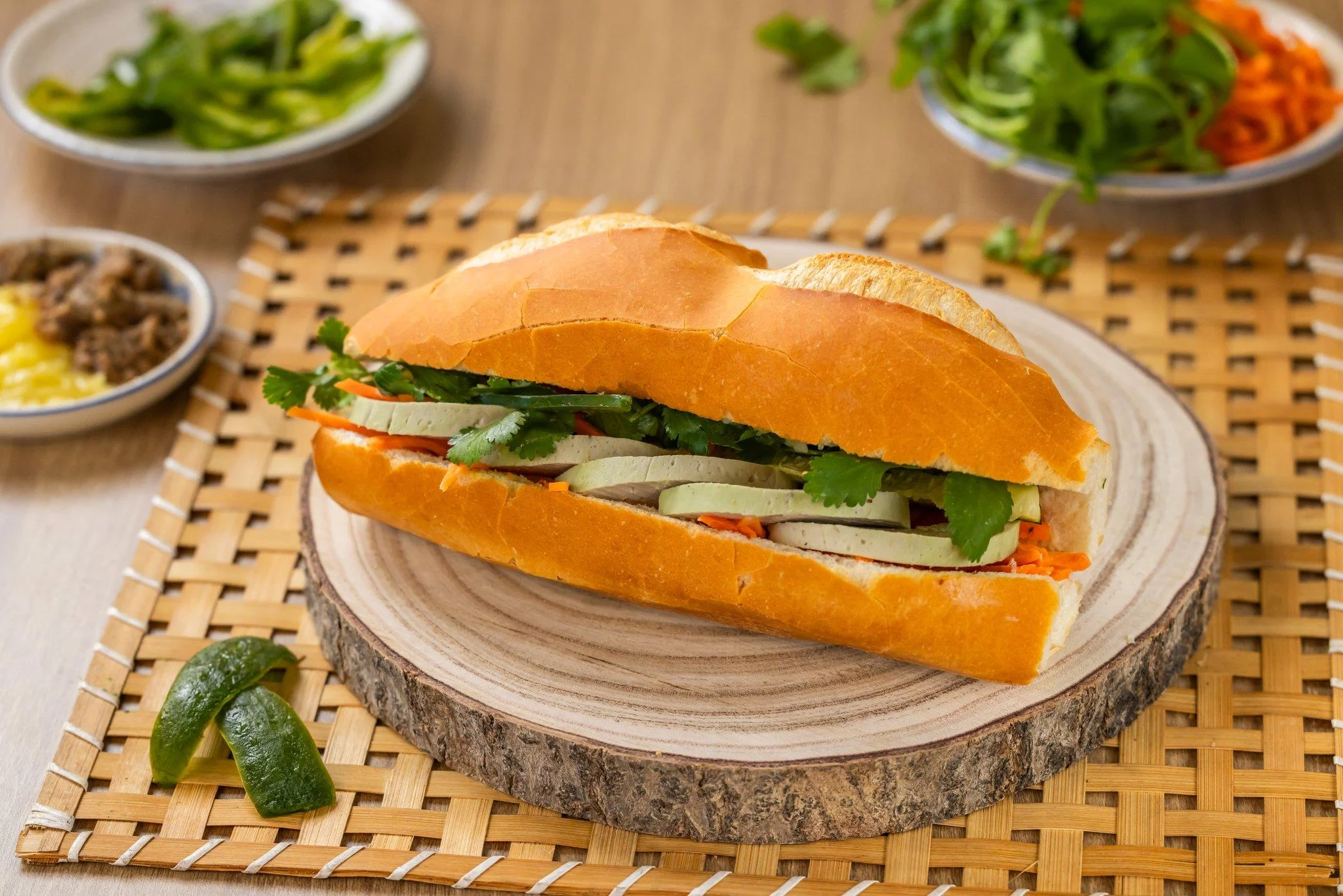 A vibrant sandwich with slices of vegetables and cilantro, served in a crunchy baguette.