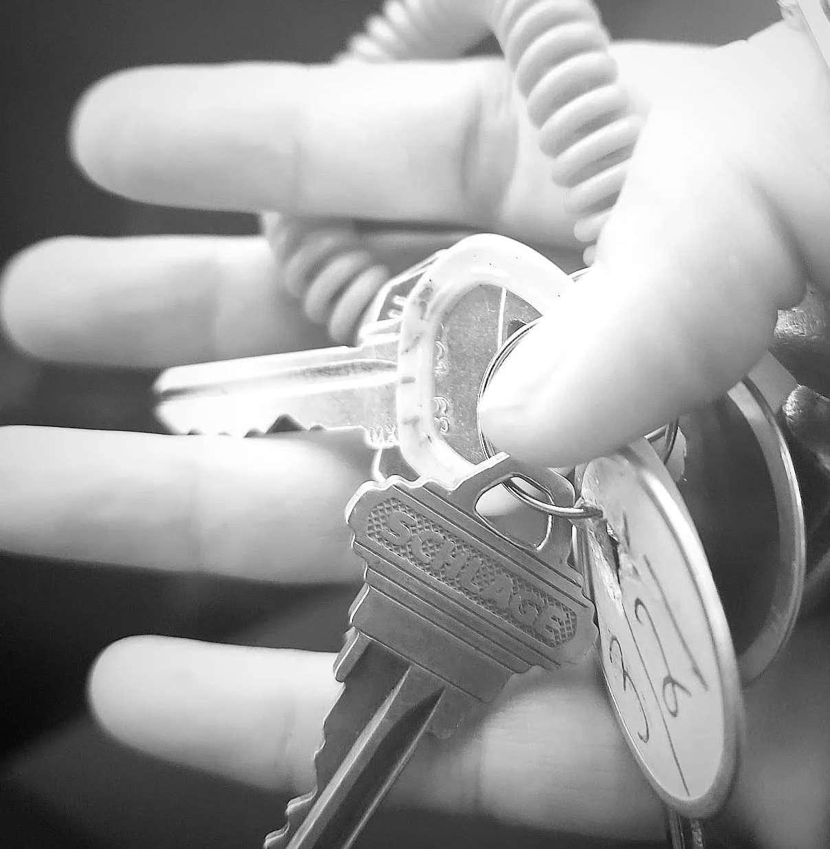 Close-up of keys held in a hand with a coiled keychain