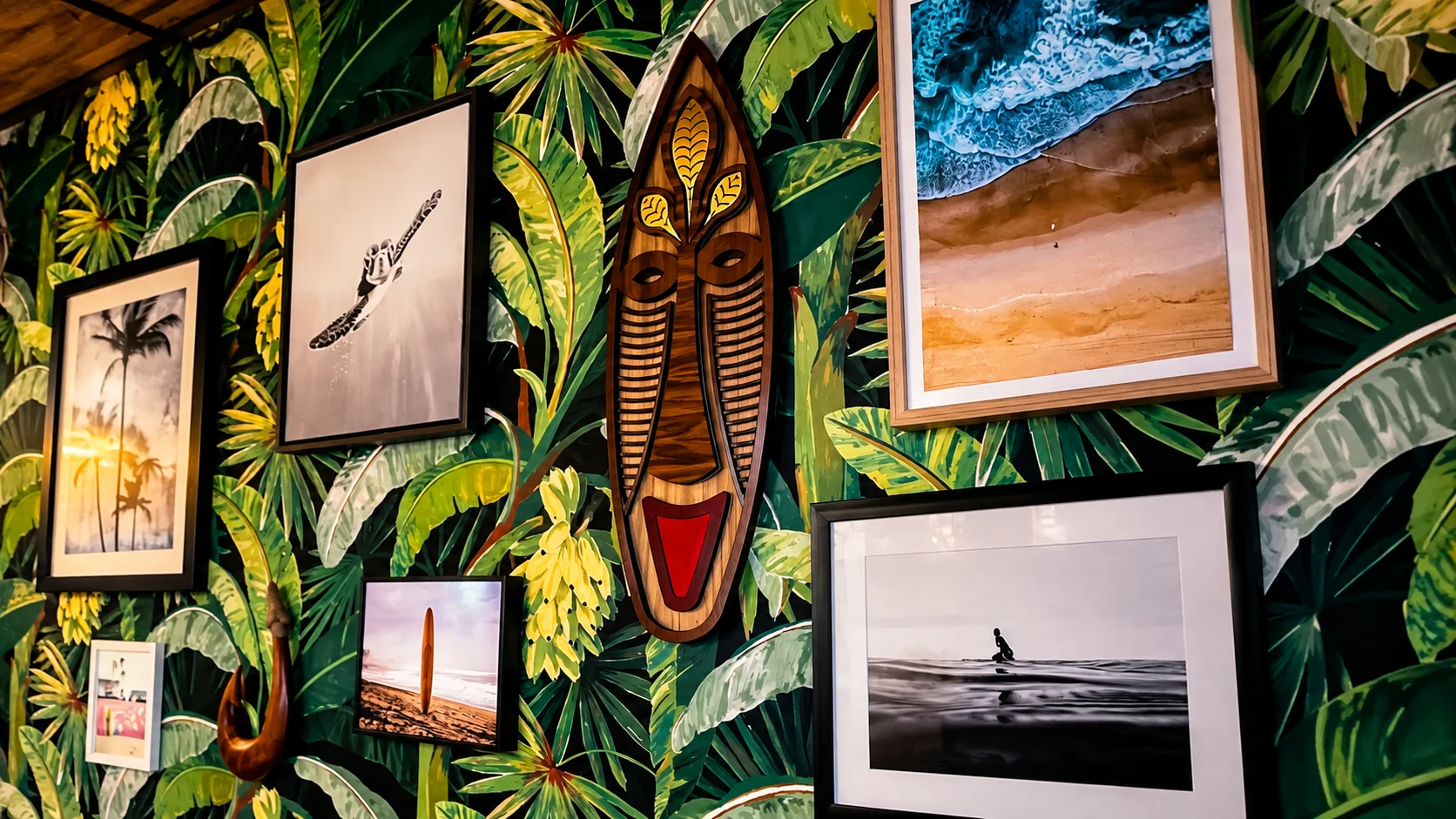 A wooden wall mask featuring abstract facial features and a tree design, mounted on a vibrant tropical leaf wallpaper.
