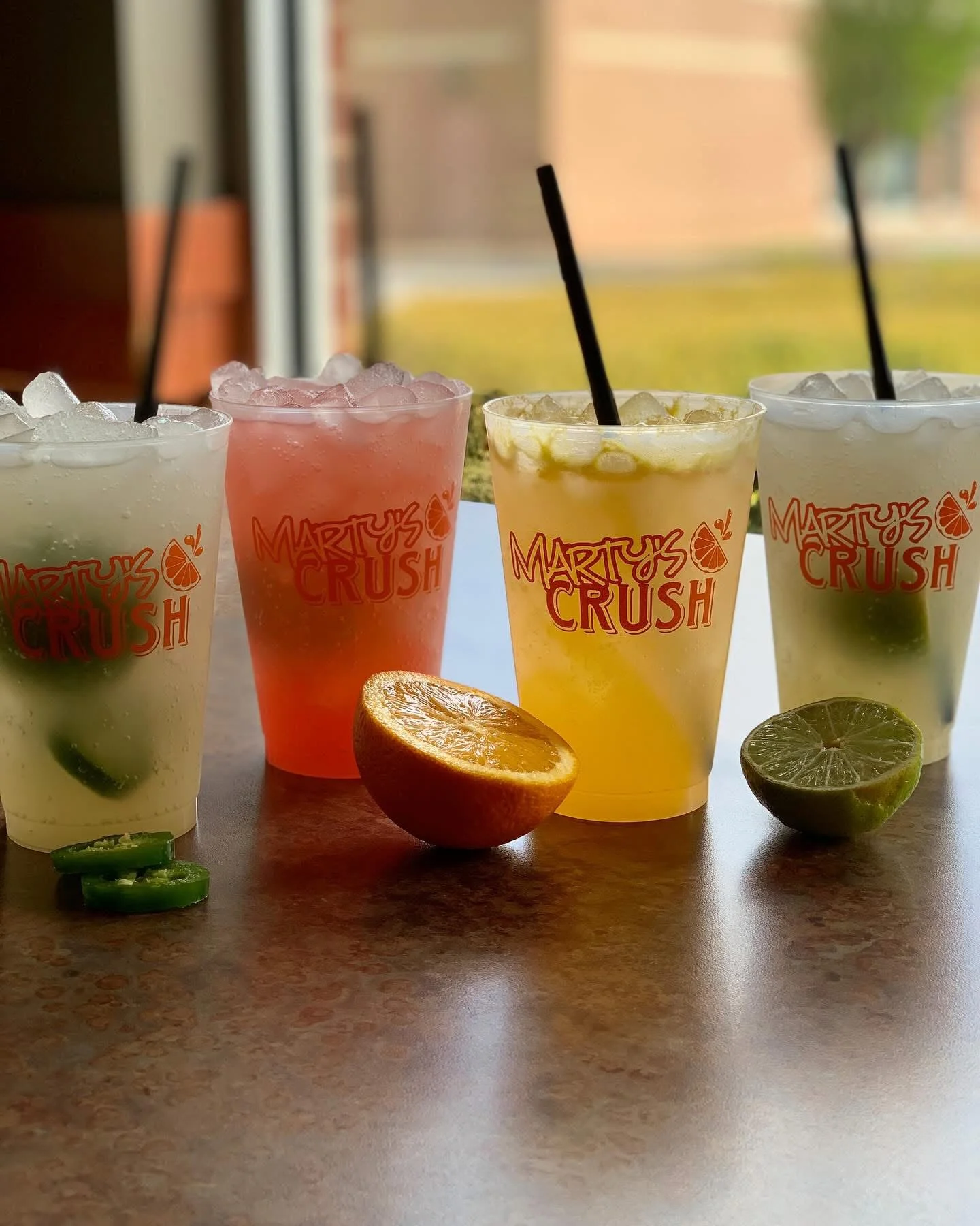 Colorful cocktails in branded cups with fresh fruit garnishes