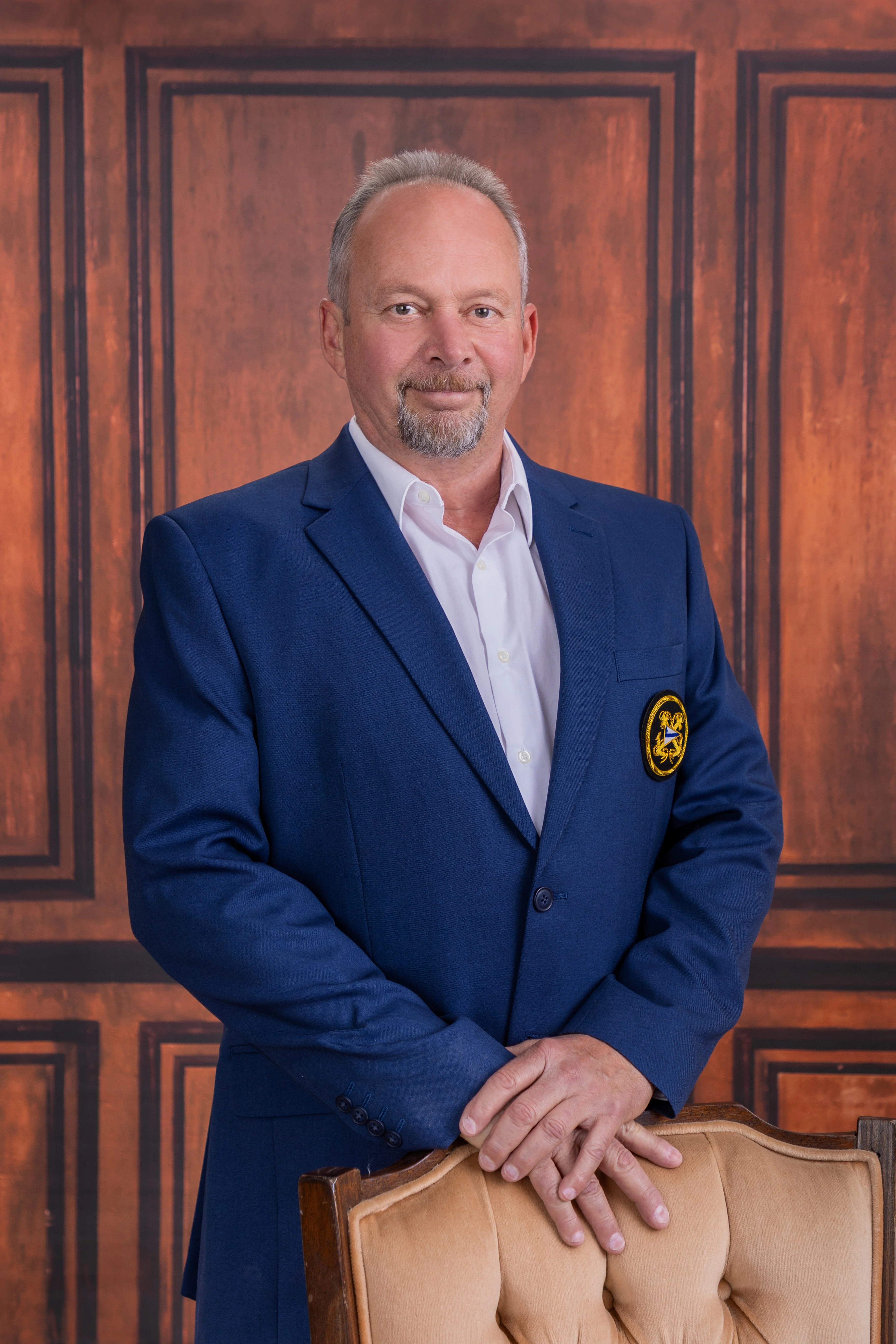 Professional portrait of a man in a blue suit with a warm background