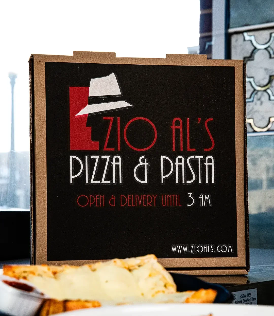 Zio Al's Pizza & Pasta delivery box with food items on a table.