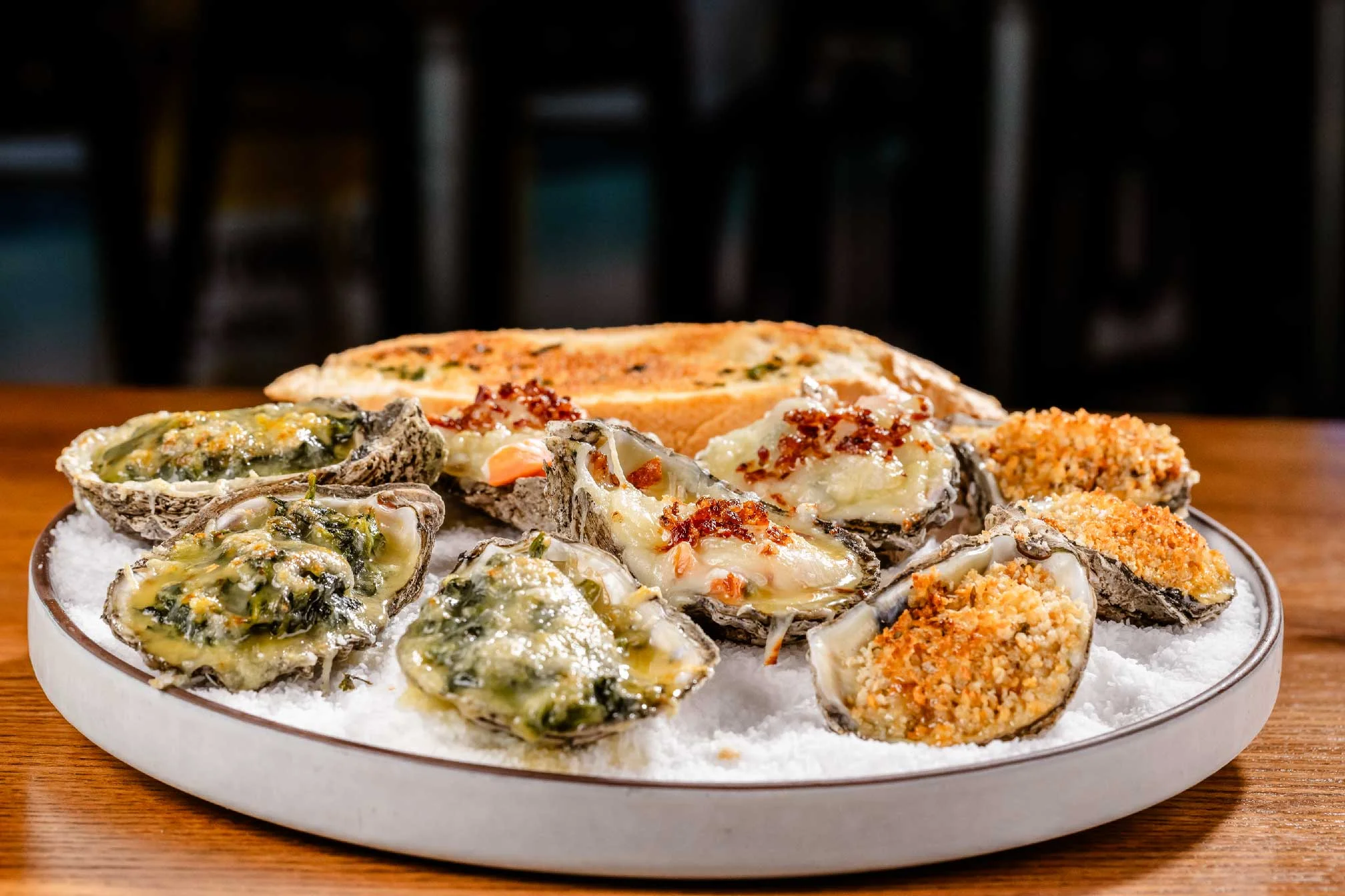 Baked oysters Rockefeller served on a bed of salt with garlic bread