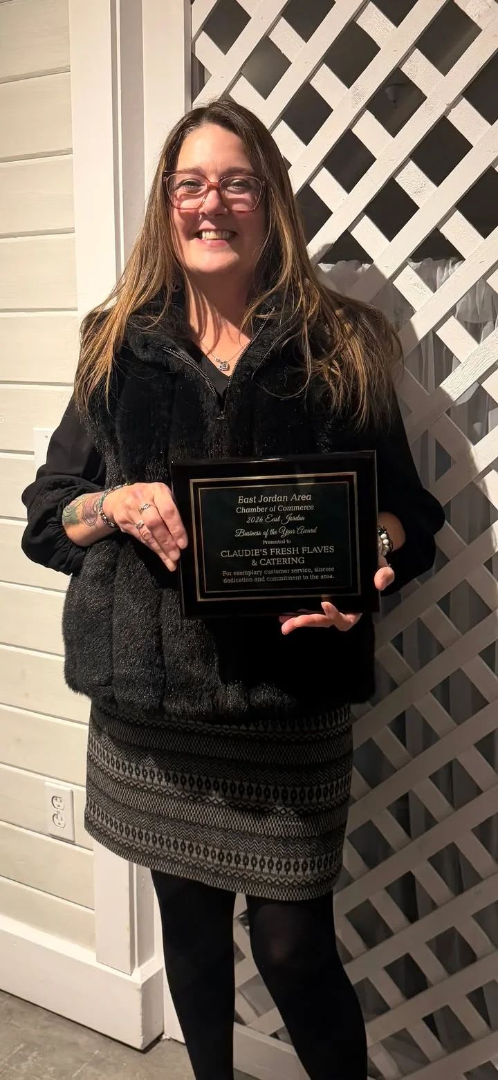 Woman holding an award plaque for Business of the Year at a restaurant event.