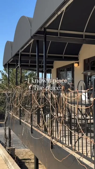 An outdoor dining area with a modern architectural design, featuring railings and planters.