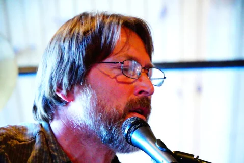 A musician playing guitar on stage at a restaurant event.